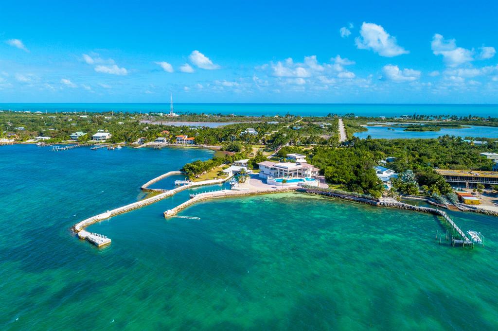 Paradise Found in The Florida Keys! Rare opportunity in Marathon, Grassy Key to own your own private compound perched on 5.5 blue waterfront acres as well as owning 5.25 Acres of Bay Bottom. This is truly a boater's dream. The private gates open and 100 Ft. Royal Palms line the driveway to welcome you and your family. Tropical breezes blow through the over 200 Palm Trees. Just off the Main House with its incredible infinity edge pool is the 2 garage boat house with private captains quarters. This property has its own private boat basin with 500 Ft private pier. A Salt water Coral Grotto with Lobster Farm. Bring your Sport Fisher, Flats Boats and Jets Skis to fish and explore all the Florida Keys has to offer from your backyard. Sip cocktails and enjoy the incredible sunsets over the bay.