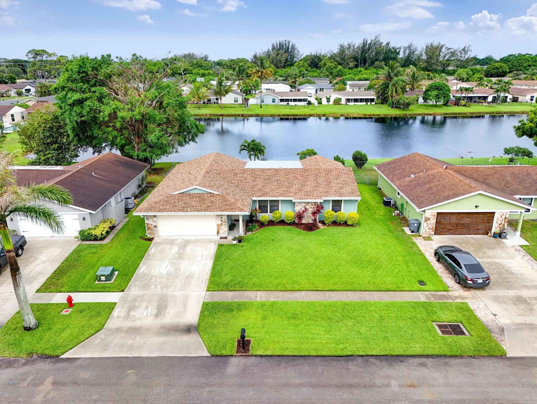 Large 4 bedroom with a 2 car garage, fully fenced lot with irrigation, lovely water view with paver patio, and December 2024 roof. Home entrance has an impressive vaulted ceiling in the living room that will impress all. Kitchen is fully updated with white shaker cabinets, stainless steel appliances, tile backsplash, pot drawers, and quartz counters. Full hurricane protection with part impact windows and impact rated garage door. Updated bathroom vanities. Master bedroom has large walk-in closet. No carpet in this home with wood look floor in the living areas and tile in the bedrooms. AC 2019 and water heater 2015. Attic has plywood decking for extra storage. Top rated school zone. 0.7 miles to Publix & other shops. 9 minutes to Boynton Beach Mall. Less than 15 minutes to the beach.