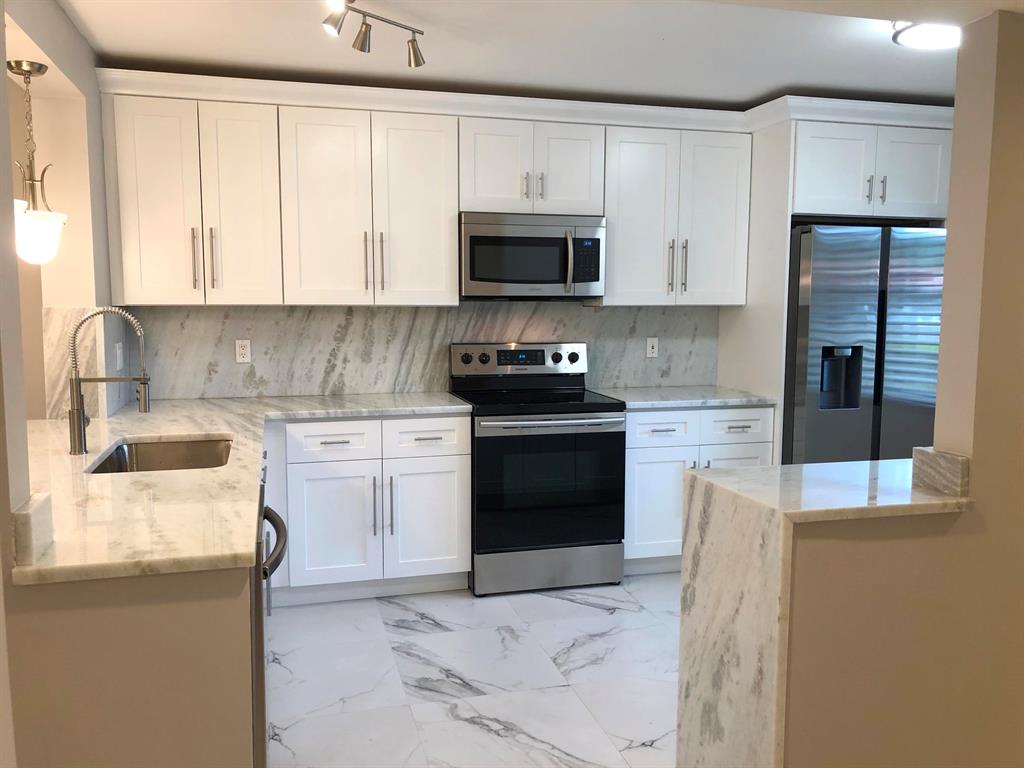Completely renovated 1st floor Chardonnay model in Huntington Pointe with private entryway and beautiful lake view. Dream kitchen w/ stainless steel Samsung appliances, gorgeous natural stone counters in modern color scheme w/ waterfall effect. All new cabinetry with soft-close doors, magnificent 24'' porcelain flooring throughout. All newly painted w/ new LED lighting, fans, doors, hardware. Baths have sliding glass doors w new vanities, toilets & matching stone counters. Split bedroom floor plan. Brand new full size Samsung washer/dryer. Screened patio overlooking lake. You will love this well-maintained community. Walk to clubhouse, pool. Great transportation. Near every amenity, beach, restaurants, hospital and I-95. Absolutely nothing to do. We did it all. Just move in and enjoy life!