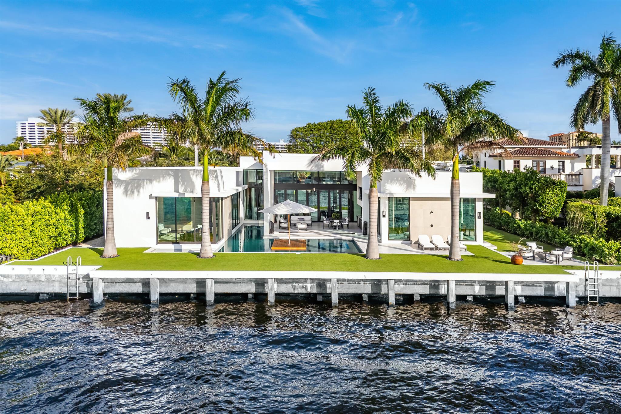 Introducing 1801 Spanish River Road - A Modern Seaside Masterpiece on the Intracoastal. This stunning, single-story estate combines sleek design with waterfront luxury, offering 109 feet of prime water frontage and sweeping views of Boca Raton's exclusive Intracoastal waterways. Step through the private, gated courtyard over a bridge flanked by serene reflecting ponds and arrive at a masterpiece encased in glass. The residence features sophisticated design elements throughout, including a grand 10-foot-tall pivot entry door, soaring ceilings, and a transparent 168-bottle wine wall. The great room dazzles with a backlit fireplace and a 26-foot-long Eurowall folding door that seamlessly connects indoor and outdoor living on the rear lanai. The custom Poggenpohl chef's kitchen