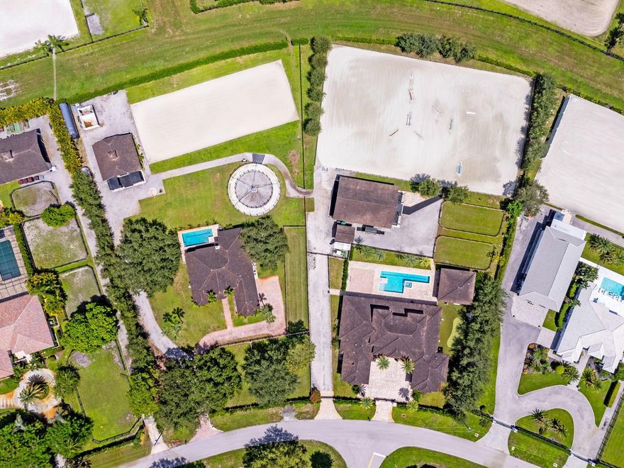 An equestrian dream opportunity: two adjoining properties totaling 3.75 acres with world-class equestrian facilities, including a fully equipped 7-stall barn with tack, feed, laundry, and full bath; a 5-stall barn with tack and feed rooms; multiple wash stalls; two sand arenas; a hot walker; and five paddocks. Three gated driveways and mature landscaping provide privacy and ease of access, just minutes from the Wellington International, Global Dressage venues, and Wellington's dining and shopping--perfectly timed for show season.The main residence is a modern entertainer's dream with bright, wide-open spaces, soaring ceilings, and nearly floor-to-ceiling windows. The entry leads into a striking, one-of-a-kind wine room. Italian marble and wood flooring flow throughout,