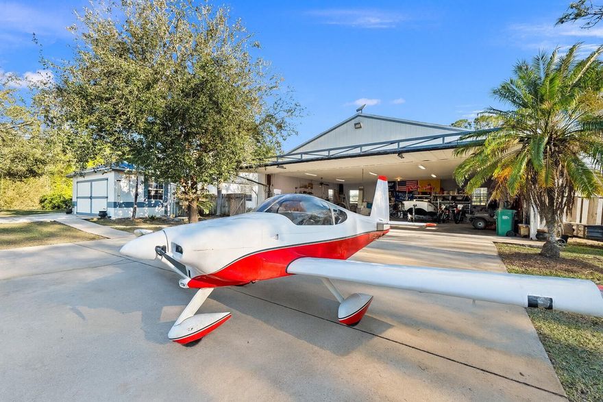 Discover this exceptional 3 bedroom, 2 bathroom custom-built home on 2.76 acres AG-5 zoned lot in the prestigious Treasure Coast Airpark (FL 37). A rare opportunity to own a hangar home adjacent to one of South Florida's longest hard-surfaced runways, this property offers direct taxiway access to a 4,000 ft lighted asphalt strip accommodating aircraft up to 12,500 lbs. The detached 50x50x10 hangar features a hydraulic swing door, fits up to a 40-ft wingspan plane, and includes a shed for tools or workshop space. Recent upgrades include new 2023 roofs on both home and hangar, 2022 A/C, Culligan water system, and central vacuum. Inside, enjoy vaulted ceilings, tile throughout, a wood-burning fireplace, and a kitchen complete with stainless steel appliances, gas cooktop, and double ovens.