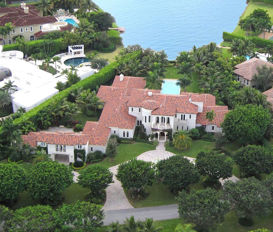 Newly renovated throughout, this Contemporary-inspired lakefront estate captures a long southwesterly water view from 1.43+/- acres of tropically landscaped grounds.  The stately main residence is accompanied by separate self-contained guest quarters in the carriage house, which has a drive-through bay to a discreet parking court by the five-bay garage.  A columned loggia centers on the lake view across the 65+/-foot-long vanishing-edge pool and spa lined by statuesque palms on lush lawns that sweep to the shore.  Another loggia serves as an outdoor living/dining room with an elegant fireplace, a summer kitchen, and full cabana bath.