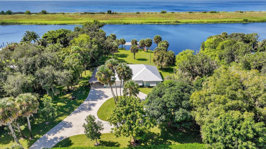 What we have here is a unicorn location!  Situated on 1.214 acres of private land with over 450' of waterfrontage that stretches across the back and along one side of the lot.  These listings don't come up for sale very often, so don't delay in checking out this solidly built 2221 SF CBS home.  Whether you're into boating, fishing, kayaking, or just enjoying nature at your fingertips, this is a prime spot for it all!  Backed up to the Rim Ditch/C-24 canal and right next to the Locks to bring you into Lake Okeechobee, we've got the best spot in town. Enter the fenced and gated yard and you can immediately appreciate the yard space.  You'll have parking for everyone on the long driveway with circular extension.  There is a covered carport for protecting your toys, as well as a 2-car garage, Launch your own kayak or boat on your own ramp with boathouse cover or chill on the covered dock and watch the wildlife.  On the land, you'll have room to let your imagination run wild.  Grow your own food, raise your own animals, build a pool, do whatever makes you happy!  You'll inherit fruit trees such as avocado, mango, banana, and loquat too!  The mature trees give an amazing canopy of shade for the ultimate in relaxation.  I can just picture you in that hammock!  The metal roof was replaced in 2018, so no worries about the roof.  On the inside, you'll find a welcoming foyer entry that opens up to the large living room.  The kitchen has lots of counterspace for prep and limitless storage with 2 big pantries.  Island cooktop with separate wall oven/wall microwave combination.  You'll get to enjoy the view while washing dishes at the kitchen window.  Eat-in kitchen with a full dining area, so you can take a pick where to eat.  As if the living room weren't big enough, there's also a den, so no arguing over who's watching what on the TV! You'll find a bonus room extended off of the primary bedroom, a great place for a dressing room, office, nursery, reading room...you decide the best use of that space.  Interior laundry room with more storage space.  The home is on well and septic, which helps with utility costs.  The well has a full softener and treatment system with a whole-house reverse osmosis system.  There's so much more to know, but you'll just have to call and make an appointment!