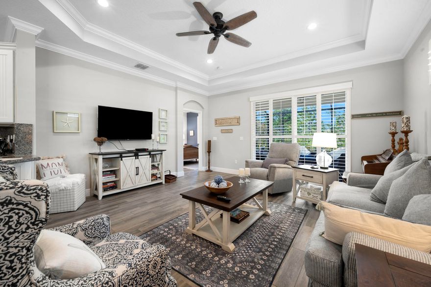 Welcome to this beautifully upgraded villa in a serene and secure 55+ gated community. Designed for comfort and luxury living, this home boasts an array of high-end features and upgrades throughout. Step inside to find elegant tile plank flooring that extends seamlessly throughout the entire home. Impact-resistant windows and doors offer peace of mind. The open-concept living space is enhanced by tray ceilings, crown molding, and plantation shutters, creating a warm, inviting atmosphere. The chef-inspired kitchen is a true highlight, featuring upgraded cabinetry with convenient pull-outs, sleek granite countertops & backsplash, and premium stainless steel appliances. Pendant lighting above the expansive counter adds a touch of sophistication, perfect for both cooking and entertaining. Th