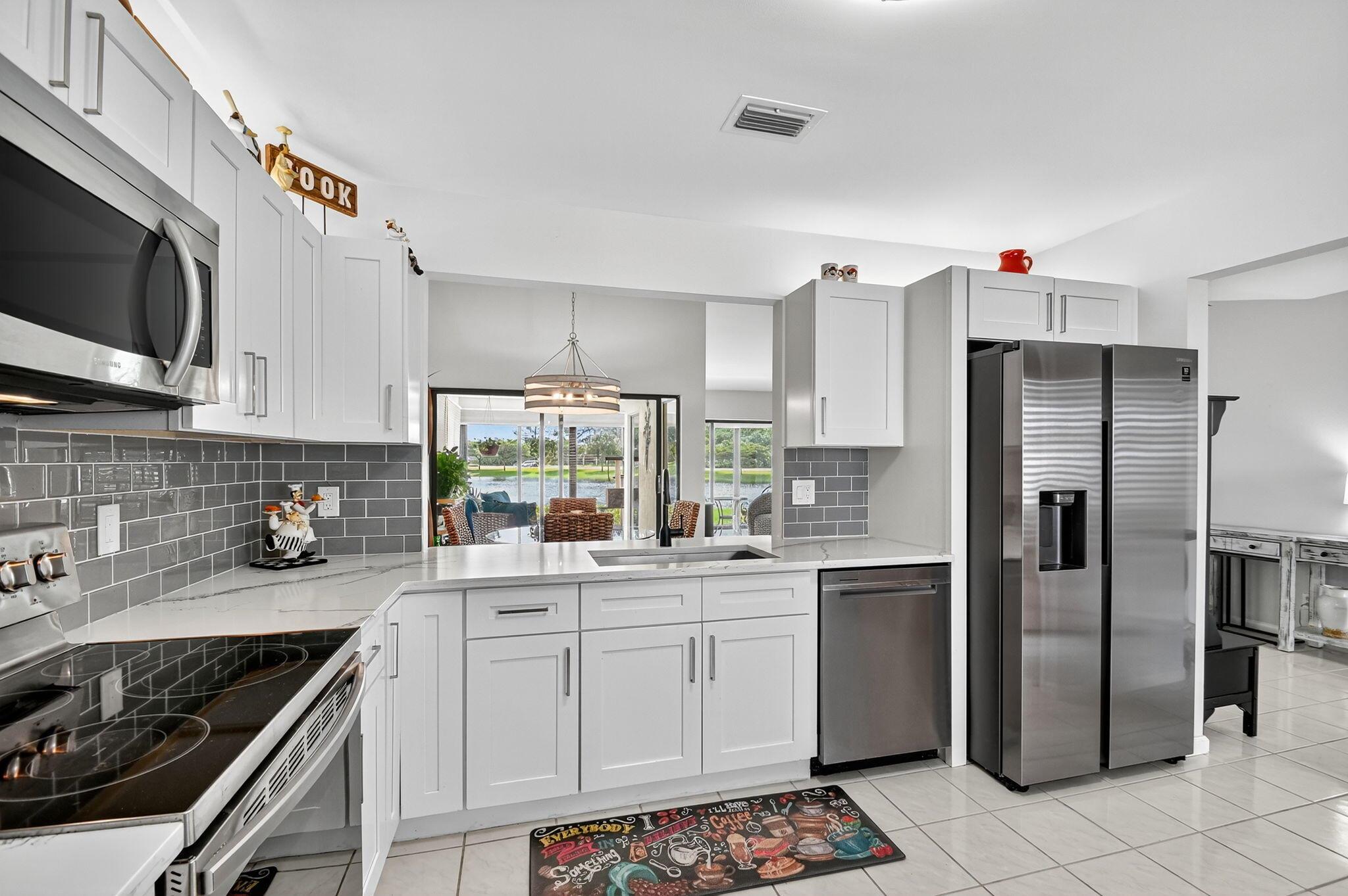 Start your mornings w/coffee & peaceful lake views, welcome to the ultimate Florida lifestyle! From your expansive air conditioned lanai, enjoy year round indoor/outdoor living & sunsets that make every day feel like vacation. This beautifully updated home features a split floor plan, soaring ceilings, & tile flooring throughout. Entry w/motion-sensor lighting, a covered front porch & a carport w/tons of storage. Enter with a secure Anderson storm door as once inside, natural light pours into the spacious foyer, formal dining, & open living areas. Modern kitchen w/newer appliances flow seamlessly into the dining & living rooms, all overlooking the lake. The primary suite also boasts serene water views and updated bath. The wraparound air-conditioned patio, expands your living space beyond