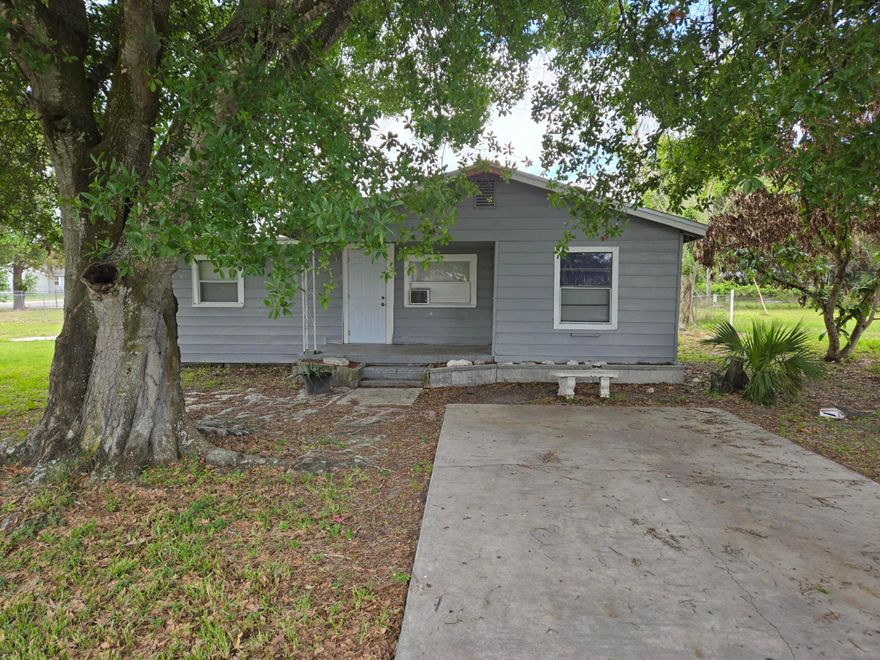 **Charming Okeechobee Farmhouse on Oversized Corner Lot!**  Discover the perfect blend of classic charm and modern convenience in this original Okeechobee farmhouse! Nestled on a spacious corner lot adorned with majestic shade trees, this home offers endless potential for expansion, including room for an in-law suite. Step inside to find a partially updated interior featuring NEW hardwood flooring and a contemporary bathroom (2023). The updated kitchen is ready for your culinary creations. With a NEW roof (2024) and fresh siding on the back base, this home is poised for easy living. Ideal for families or as a savvy investment opportunity, this property places you right in the heart of Okeechobee. Enjoy the convenience of being within walking distance to downtown shopping, dining, and entertainment. Explore family-friendly attractions like Flagler Park, and take advantage of the nearby parks and trails for outdoor recreation. Go fishing at Lake Okeechobee.  With city utilities and paved roads, this is a fantastic find in a city known for its Southern hospitality. This is Priced to sell quickly—don't miss your chance to make this delightful house your own! Call today to schedule your private showing before it's gone!