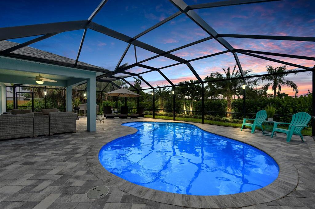 Custom built by Groza Builders Inc in 2018, this concrete block Pool Home is located in the sought-after Becker area of Port St Lucie, FL. 4 bedrooms, 2 bathrooms, a 3 car garage and a backyard oasis featuring a new paved deck & saltwater pool. With new construction you will have peace of mind for decades to come! Plus reduced energy and insurance bills! Featured inside the home are plantation shutters throughout, brand new vinyl plank flooring and a chef's kitchen with a large island and extended cabinetry. This open floor plan creates a great space that flows from the lush tropical gardens with screened in salted pool area to an open concept kitchen and living area. Large paved lanai was built in 2020. Great for entertaining! Lawn area was recently re-sodded and is irrigated.