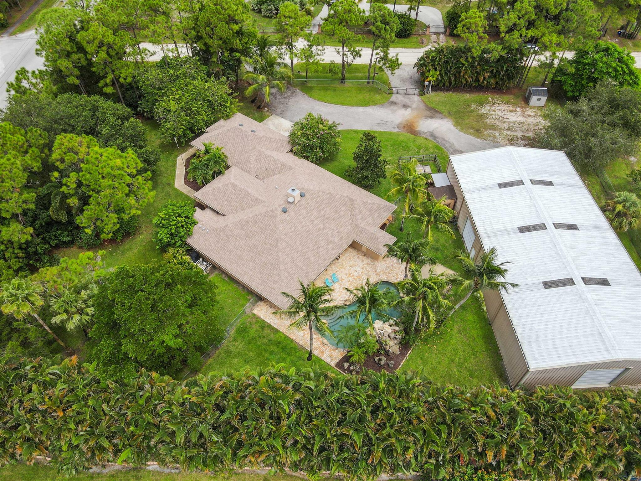 Welcome to this incredible single-family pool home with an oversized attached garage & a huge detached 5,000 sq ft garage/workshop, a true masterpiece of space and serenity, perfectly situated on a prime corner lot spanning 1.75 acres in The Acreage. With a new roof (2023) and no HOA to contend with, you'll enjoy peace of mind along with unparalleled freedom and privacy. This residence features 4 bedrooms and 3 full bathrooms, meticulously designed to offer both comfort and elegance. The spacious and open living area serves as the heart of the home, complete with a cozy fireplace and a sliding door that provides seamless access to the patio.