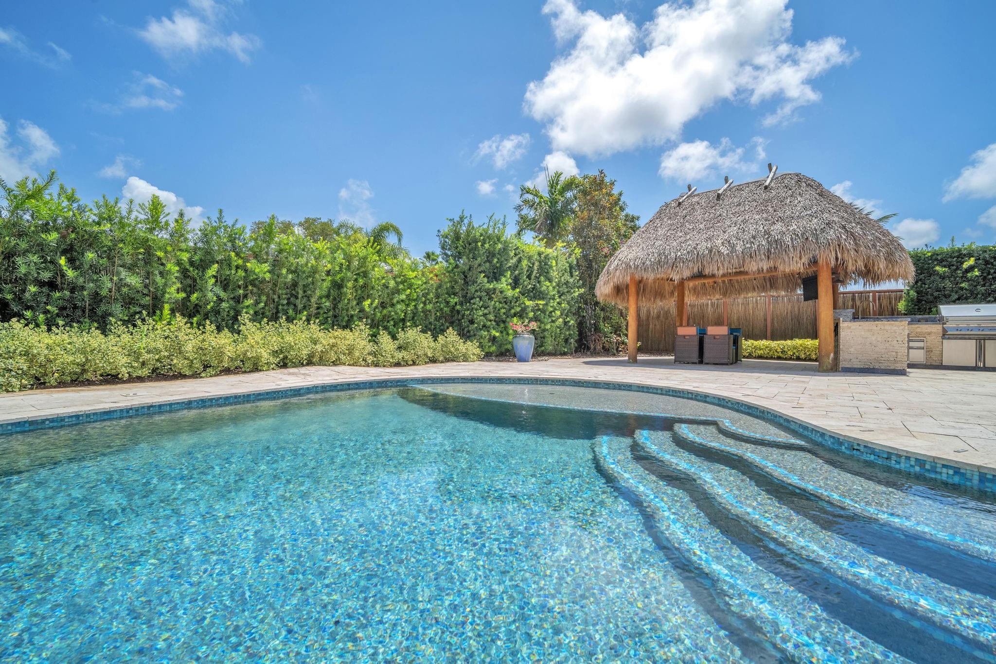 Discover this beautifully upgraded 4BD/3.5BA home in Emerald Hills, where indoor elegance meets outdoor luxury. Situated on a quiet, tree-lined street with lush landscaping, this home offers a perfect blend of comfort and style. The backyard is an entertainer’s dream, featuring a heated pool with travertine pavers, a tiki hut, and a fully equipped outdoor kitchen with a premium propane grill, sink, refrigerator, and ice machine. Inside, enjoy hurricane-impact windows, plantation shutters, and a brand-new kids’ bathroom. Recent updates include new plumbing 2018, flat roof re-coated in 2023, and a split AC unit installed in 2022. The 2-car garage offers a sealed floor and built-in workbench. Offering privacy in a prime location this home is 5.3 miles to the beach and 2 miles to the I-95.