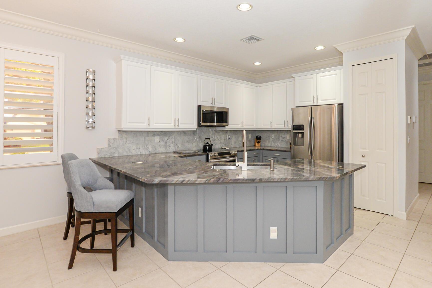 Fabulous Villa in Willow Pines at PGA Village. This lovely home shows like a Model! Wonderful corner lot with upgraded landscaping & lighting. Features 2 BR's, 2 BA's, LG Den/office & 2 Car G. Boasting screen enclosed Private lanai w/ extended patio area & hurricane Smart Screen with garden view. Spacious Living/dining areas & gorgeous updated kitchen includes quartz counter tops with tile backsplash, stainless steel appliances, new faucet, breakfast bar & pantry. Open floor plan with all usable space, tile in main areas & laminate is BR's & Den, volume ceilings, warm colors, Plantation Shutters & move in condition. Laundry Room has washer/dryer combo in one with cabinet for storage. Front glass door entrance & hurricane shutters complete. Closet w/ built-in's & extra storage in garage.