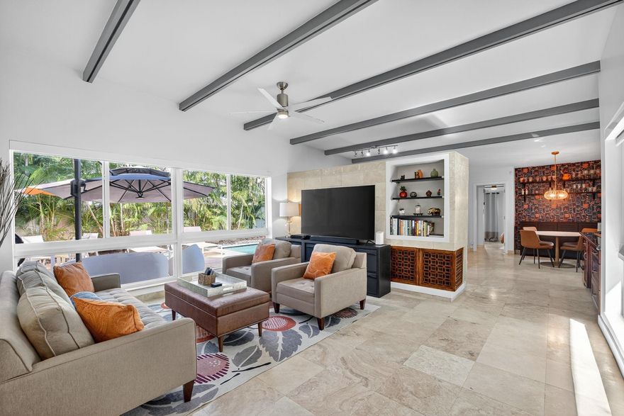 Mid-century charmer on a prime corner lot in East Wilton Manors! This stylish home features vaulted ceilings, built-ins, and a split-bedroom layout for added privacy. The main entertaining area is flooded with natural light and over-looks the lush landscaping with upgraded lighting that sets the mood day or night. Step outside to your private oasis with a beautiful pool, hot tub, and plenty of space to entertain. The sewer lines have been updated for peace of mind. A true gem combining character, comfort, and convenience!