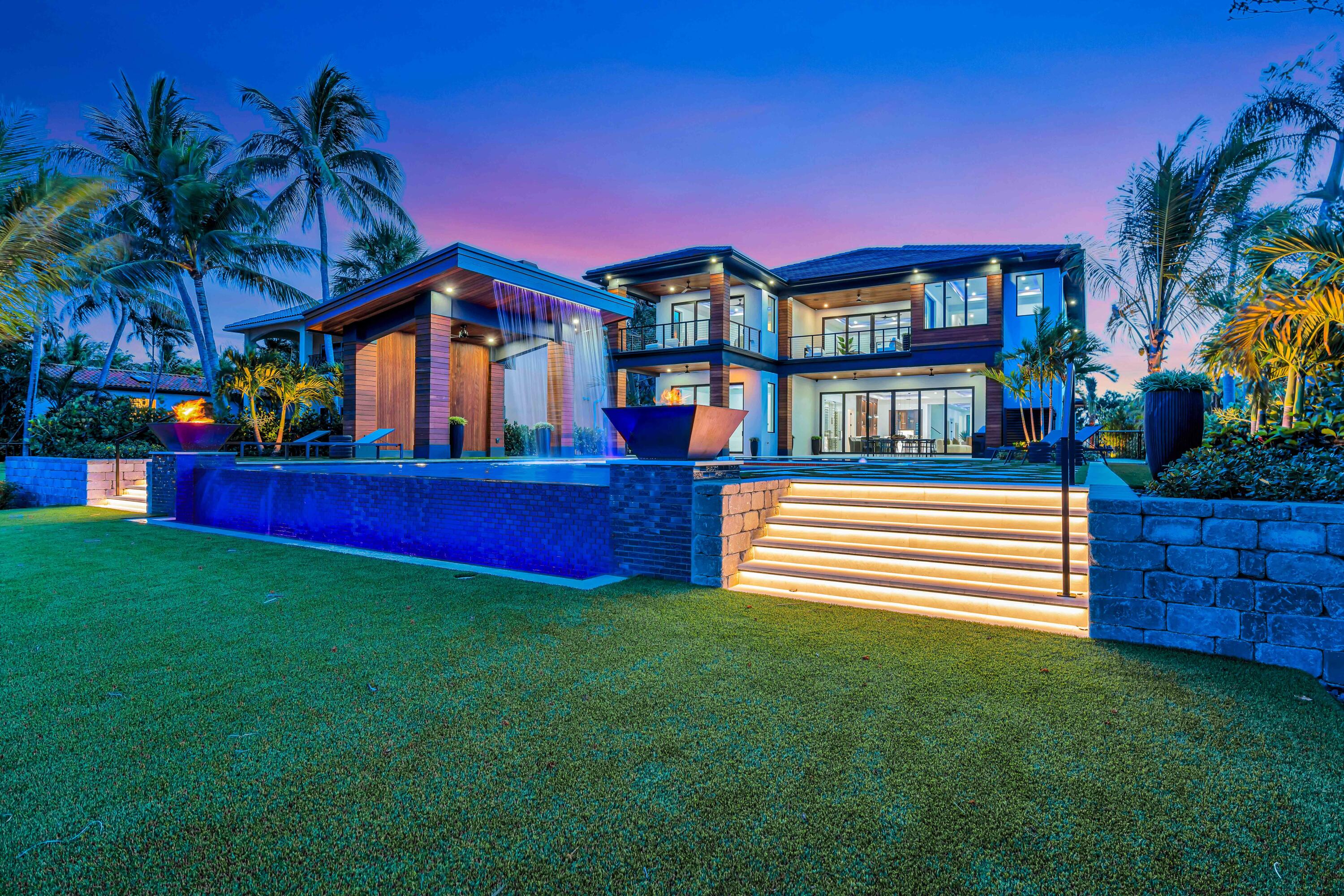 Brand-new gated intracoastal estate in prime Lantana location! Walk to the beach, Eau Resort & Spa, and top dining spots. Just 1.5 mi to I-95, minutes to PBI & private jet access. This smart, energy-efficient compound offers ultimate privacy with unobstructed water views, upstairs/downstairs living rooms & master suites. Loaded with upgrades: Sonos, security, landscape lighting. Backyard is a showstopper--$500K+ resort-style pool, sunken firepit, waterfall gazebo w/ 10 stools, and multiple fire features. Luxury living at its finest!