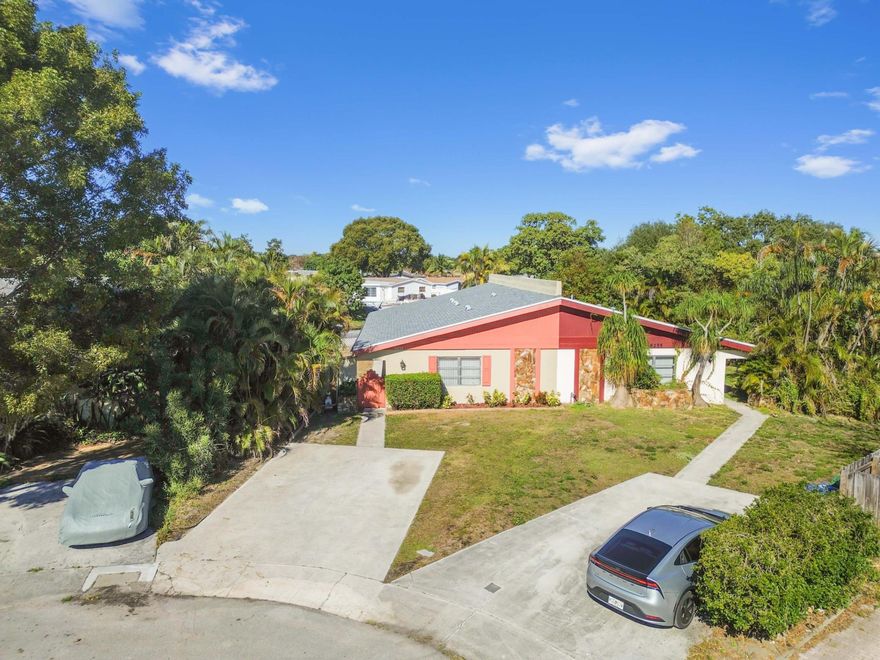 Welcome to this captivating waterfront retreat where soaring vaulted ceilings and vibrant natural light create an immediate sense of space and warmth. The heart of the home is the open-concept kitchen, featuring rich wood cabinetry, a stainless steel refrigerator, and a generous breakfast bar that overlooks the dining area—perfect for casual entertaining or morning coffee. Cool tile flooring flows effortlessly through the main living areas, leading to practical conveniences including a dedicated laundry room with overhead shelving and a separate utility room that offers abundant storage space. Relaxation awaits in the expansive primary suite, a true sanctuary highlighted by high ceilings, decorative plant shelves, and an en-suite bathroom with a walk-in shower. Two additional well-sized bedrooms provide versatility for family, guests, or a private home office, each offering ample closet space. The living experience extends to the spectacular glass-enclosed Florida room at the rear of the home. With its panoramic windows and peaceful canal views, this sun-drenched space is the ultimate year-round haven for a home gym, playroom, or tranquil reading nook.