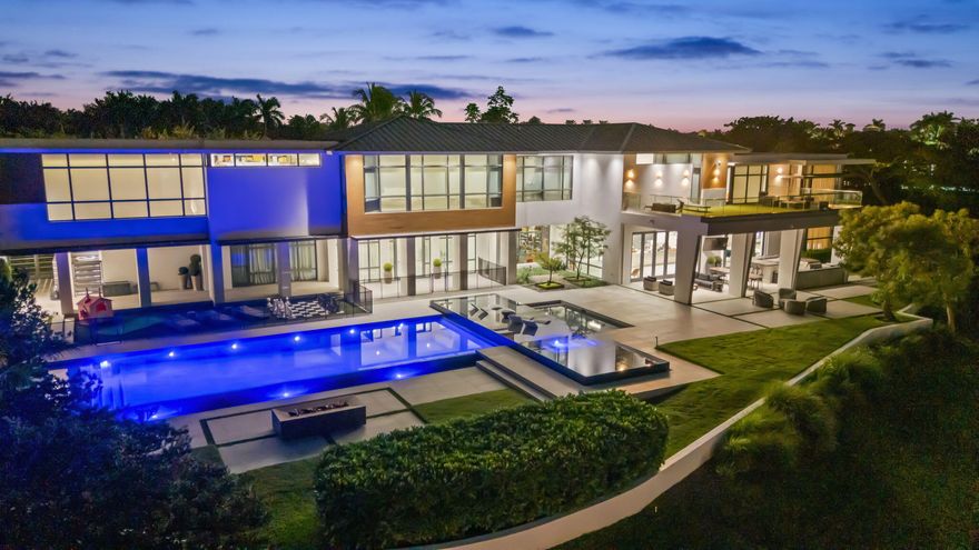 The most architecturally designed lakefront estate in the premier guard-gated community of Hawks Landing. Set on nearly an acre, this 17,400 sq ft modern residence captures light, water views, and glowing sunsets. The soaring 35-foot ceilings, dual floating steel staircases, and glass wine room define the interior. The Bulthaup kitchen opens through Nano doors to a resort-style 80' pool, waterfall, and expansive outdoor entertaining area with a full kitchen. The loft-inspired primary suite offers sliding oak doors and panoramic views. Some of the additional features include all en-suite bedrooms, a state-of-the-art gym, an 8-seat movie theatre, and a private guest house. Hawks Landing offers a clubhouse with a fitness center, tennis, pickleball, playground & 24-hour guard-gated security.