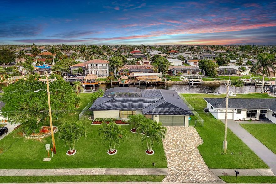 SAILBOAT ACCESS POOL HOME ON THE PELICAN FINGERS! This 4BR, 3BA home blends waterfront luxury with modern updates. A newer metal roof (2023), paver driveway (2020), fresh exterior/interior paint (2024), and lush landscaping add curb appeal. Inside, stacked tile flooring flows throughout. The kitchen impresses with ceiling-height shaker cabinets, subway tile backsplash, granite, SS appliances (2022), and a pass-through window to the lanai. The primary suite offers private pool access, dual sinks, and walk-in shower, while a guest suite also opens to the lanai. Pool bath features a tiled shower; pool recoated and heated (2022). Backyard includes new lanai (2023), fencing, sprinklers (2024), and a pavered walkway to dock/boat lift. Minutes to Tarpon Point, shopping, dining, and Rotary Park.