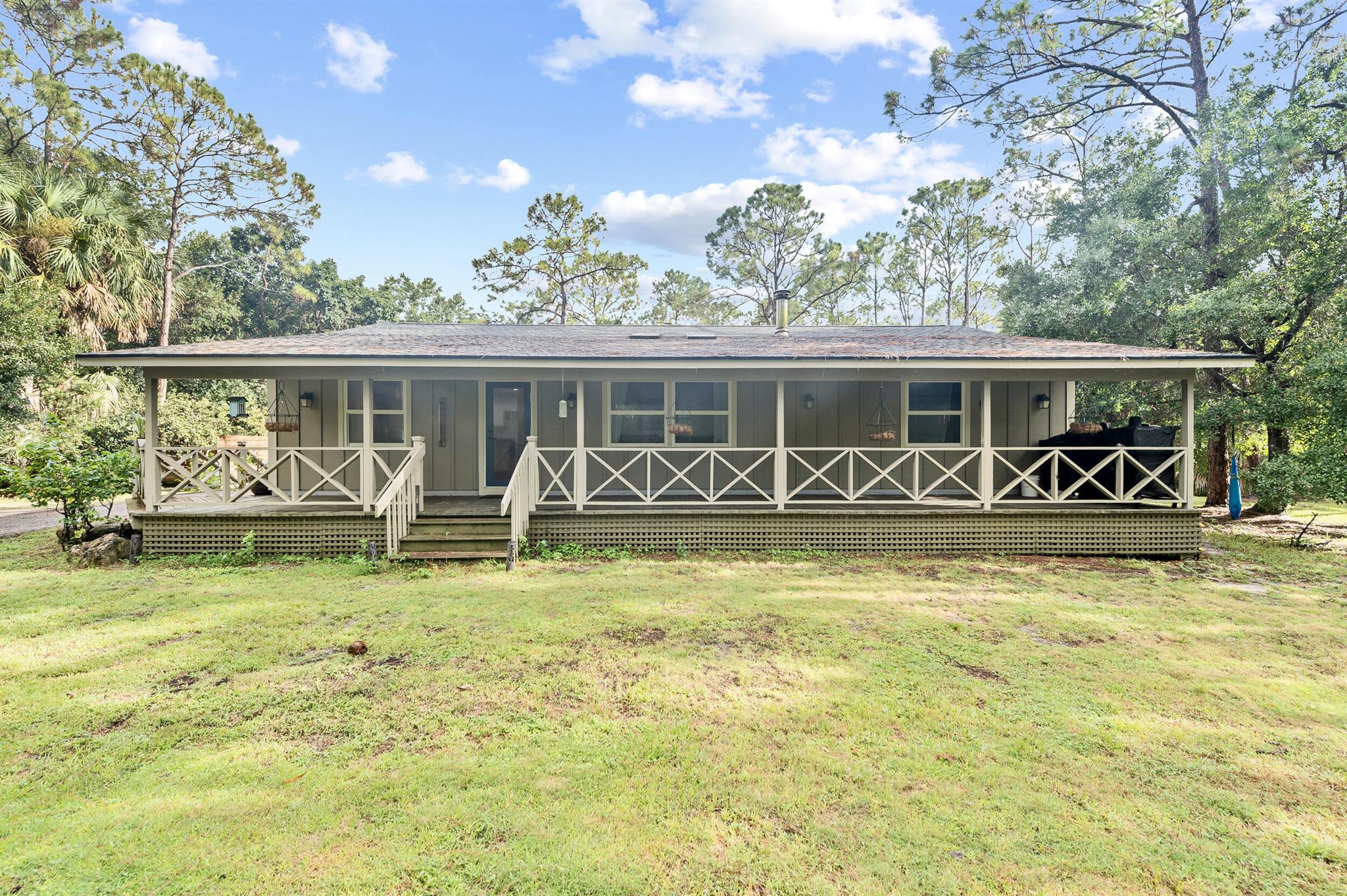 Set on 1.35 fully gated acres, this renovated 3- bed, 2-bath farmhouse retreat greets you with a wrap around porch and bright, timeless interiors refreshed in 2023 with added pantry shelving for extra storage. The grounds are ready for country living: chicken coop, goat house, and run ins for a mini cow and mini donkeys, plus back gate access to the bridle path. A detached 2-bay garage offers abundant room for vehicles, tools, or a workshop, and the hot tub is perfect after a ride. Major improvements are already handled for peace of mind: 2022 roof; PGT impact windows/doors with Impact VELUX no-leak skylights (remote blinds); 2022 fence & gate; 2021 A/C; 2021 tankless water heater; 2018 well; septic pumped 2024; generator outlet for quick hookup delivering low-maintenance living.