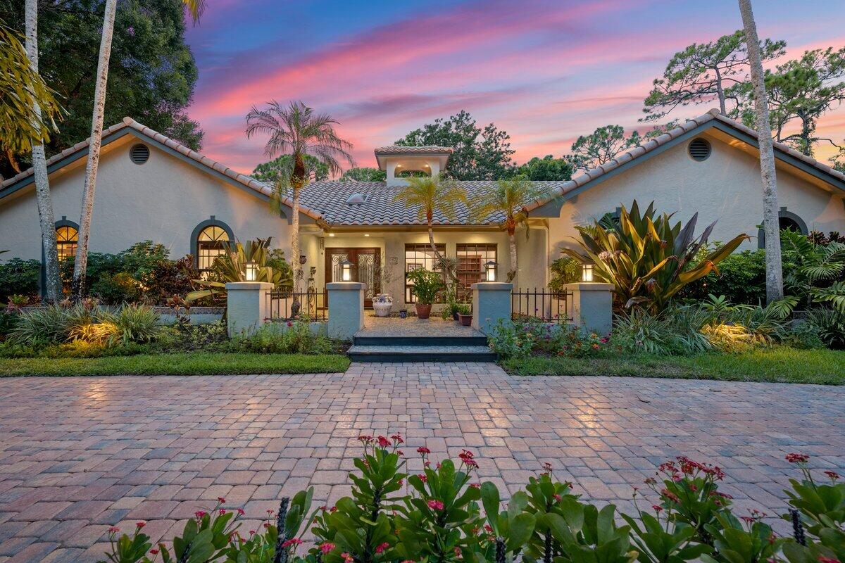 Envision arriving at a stately Mediterranean retreat, gracefully set on a premier 1.21-acre corner lot where lush landscaping frames every view and privacy feels effortless. A sweeping circular driveway welcomes you to a residence that blends timeless design with a relaxed Wellington elegance.Inside, vaulted ceilings and sunlit hard wood floors create a sense of airy sophistication, while the split-bedroom layout offers both comfort and versatility--complete with a den that easily transforms into a study, media lounge, or creative space. Thoughtful details, like two 2 car garages (4 bays total) and a 12' x 24' climate-controlled shop, enhance everyday living.Step outdoors to your personal resort: a sparkling saltwater heated pool with built-in spa, set amidst vibrant fruit