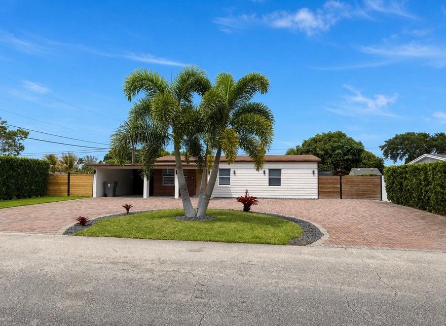 Fully remodeled 2 bed / 2 bath move-in ready home that shows like a model. Bright open-concept living, dining, and kitchen with porcelain marble-look flooring throughout, designer lighting, and modern roller shades. The custom kitchen features sleek dark wood cabinetry, quartz countertops, full-height marble-look backsplash, stainless steel appliances, deep undermount sink, and a waterfall breakfast bar with seating for three. Spa-style bathroom with frameless glass shower, marble-look tile walls, mosaic pebble floor, and floating vanity. In-unit LG washer and dryer included. Step outside to a fully fenced, low-maintenance paver backyard — ideal for entertaining, parking multiple vehicles, or future pool — plus a separate side yard with included storage shed and mature mango tree.