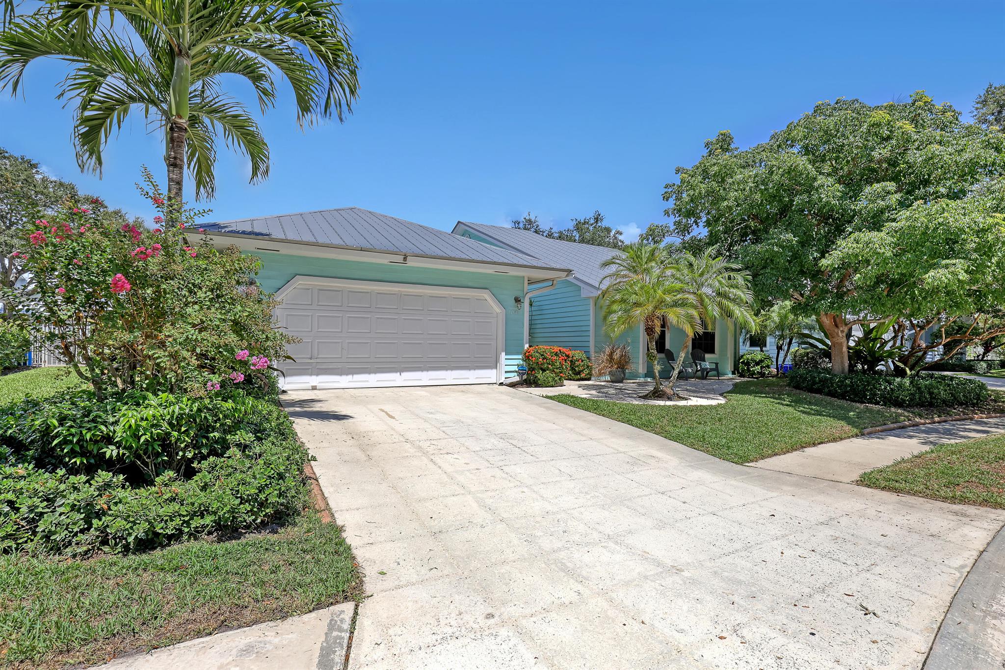 Charming Key West-Style Home with Metal Roof - This beautifully maintained 3-bedroom, 2-bath gem offers a spacious 2-car garage and numerous upgrades. Filled with natural light, the home features cheerful living spaces and large glass pocket doors that seamlessly open to the outdoor living area. The modern kitchen boasts stainless steel appliances and a brand-new refrigerator, while elegant bamboo flooring flows through the living room, dining room, and one bedroom. The backyard showcases lush, low-maintenance artificial turf, perfect for relaxing or entertaining. With a low HOA fee, designer lighting, a new hot water heater, and a newer HVAC system, this home combines style, comfort, and efficiency. Ideally located just 3 miles from the beach and close to Jupiter High School, shopping