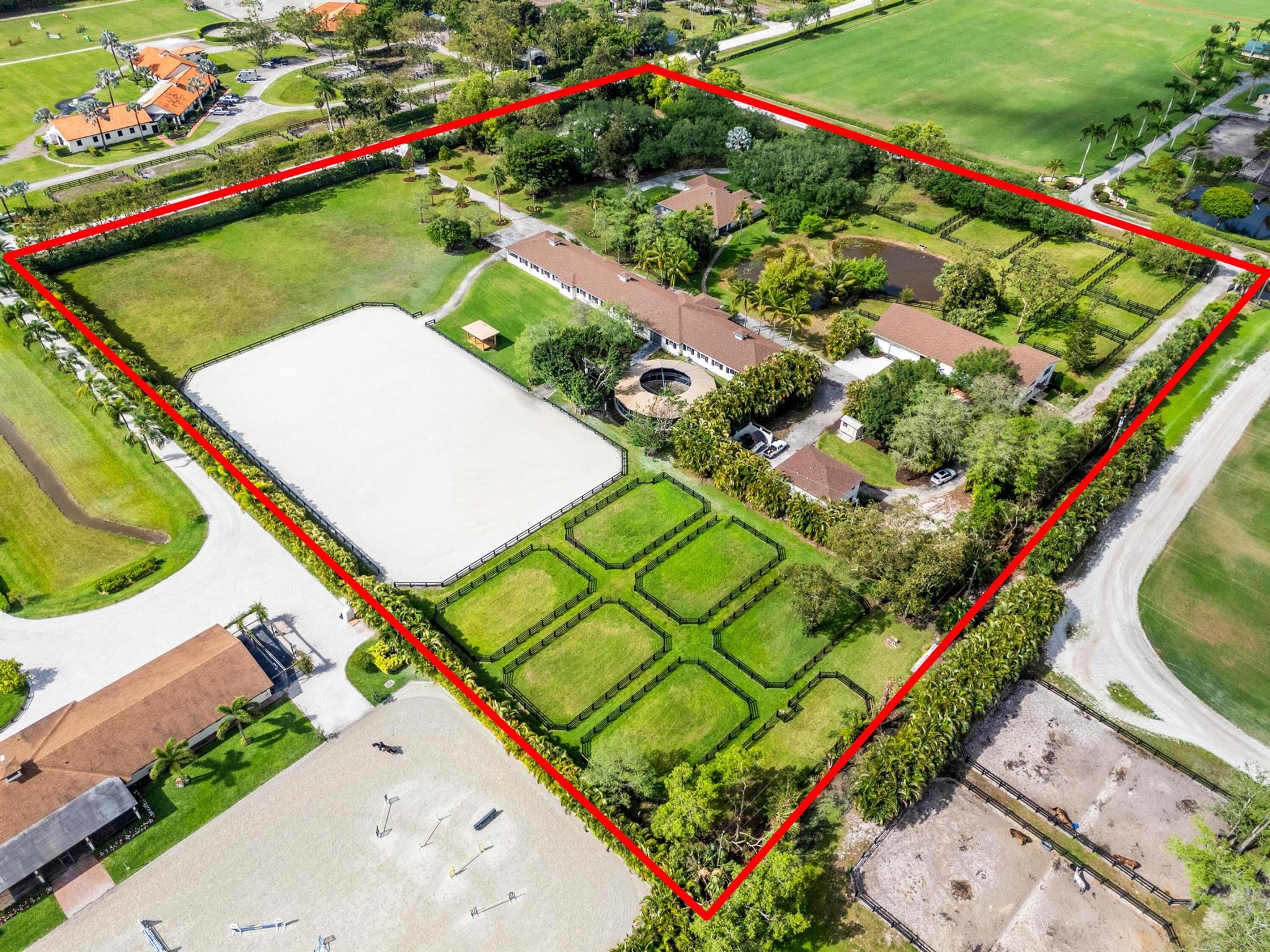 Enjoy the best of both worlds on this exceptional 10+-acre equestrian property, ideally located just minutes from Global and WEF while offering the tranquility of Wellington's farm life. This property combines top-tier equestrian amenities with luxurious living, providing everything needed for you and your horses. The 26-stall center-aisle barn is the standout feature of this property, equipped with 6 wash stalls, 2 tack rooms, a feed room, and a lounge. A separate building offers even more versatility, with a second lounge, 2 bathrooms, an oversized laundry room, and 2 spacious 2-bedroom, 1-bathroom apartments. Additionally, a huge storage area provides ample space for hay, shavings, tractors, golf carts, jumps, and farm equipment. Other equestrian facilities include 2 all weather arenas