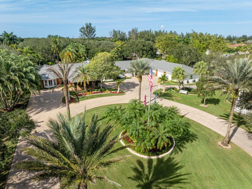 Nestled on 5 private acres, this extraordinary estate spans 10,000 SF and offers a world-class lifestyle with a full equestrian center, separate guest home, private sauna, and lush gardens featuring a gazebo and koi pond. Ideally located just 30 minutes from Miami and Fort Lauderdale airports, this hidden oasis combines luxury, security, and resort-style living. Behind grand gates, the main residence is designed for both lavish entertaining and everyday comfort, showcasing 5 bedrooms, 4.5 bathrooms, a home theater, billiards room, office, and gym. Brazilian hardwood floors, coffered ceilings, and a chef’s kitchen with marble finishes elevate the sophisticated interiors. The primary suite and newly renovated spa-like bathroom opens to a serene outdoor retreat.