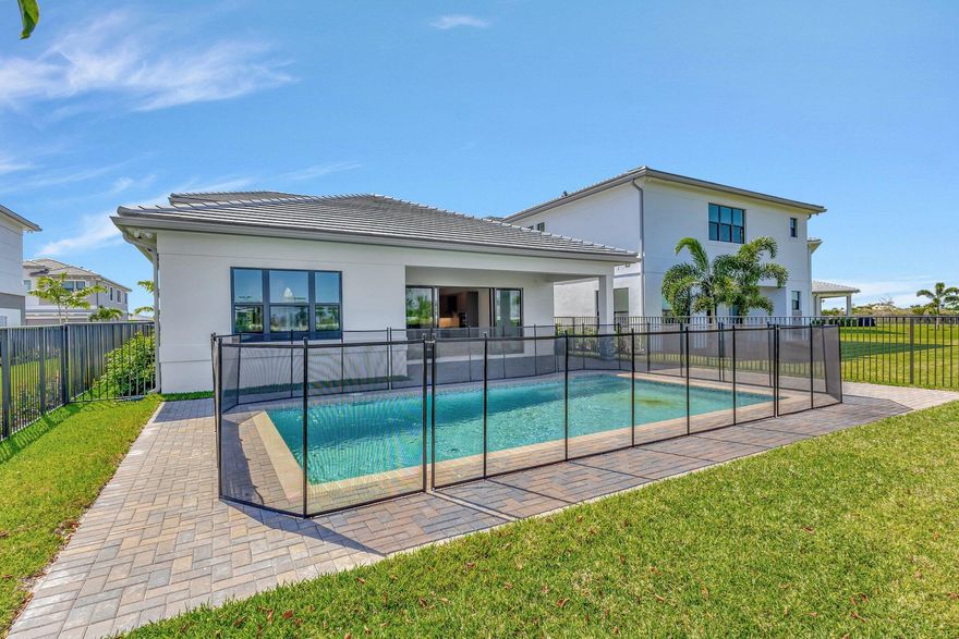 This residence in Avenir features a modern layout with open living spaces and lake views. Large sliding glass doors connect the main living area to a covered patio and private pool, creating an easy indoor-outdoor flow. Inside, the home offers large-format porcelain flooring, high ceilings, and a bright, open living and dining area. The kitchen is centered around a generous quartz island with custom cabinetry, pantry, and stainless appliances. The primary suite is located on the first floor and includes dual walk-in closets and a spacious bathroom with freestanding soaking tub, oversized shower, and double vanities. A well-designed home with clean finishes, natural light, and a functional layout in the community of Avenir. Schedule your private showing today.