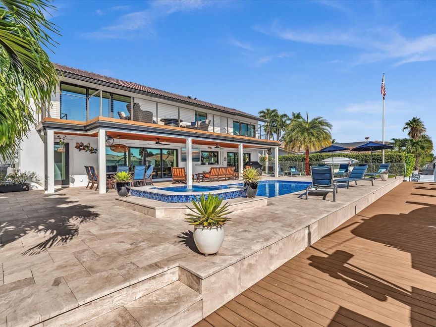 Discover this beautifully remodeled 5-bedroom, 5-bathroom waterfront residence in desirable Lighthouse Point. Nestled on a quiet street, this home is ideal for those who love outdoor living and entertaining. With 80 feet of waterfront and direct access to both the Boca and Hillsboro Inlets, it is truly a boater’s paradise. A brand-new seawall, dock, and two boat lifts were installed in 2021.
The backyard has been completely reimagined to maximize space and capture stunning water views. The heated pool features a sun shelf and raised hot tub, surrounded by new travertine decking and turf. An expansive upstairs terrace offers the perfect vantage point for unwinding at sunset