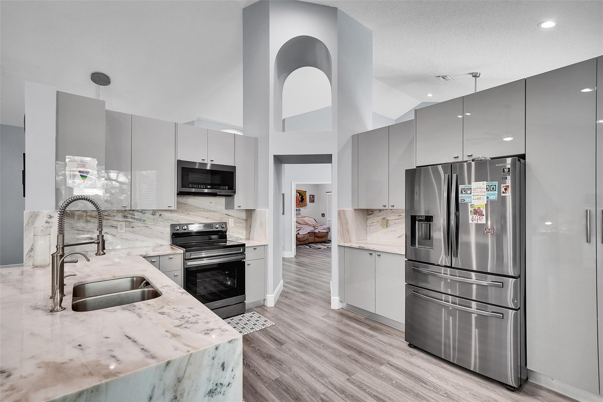 This beautiful home offers an ideal blend of style and durability! Major updates include a 2018 roof and water heater, along with high-impact windows and doors for enhanced security. Inside, the heart of the home is its sleek European-style kitchen, boasting gorgeous, one-of-a-kind quartzite countertops and backsplash, plus stainless steel Samsung appliances. Modern vinyl flooring and recessed lighting flow throughout. Parking is a breeze with an expansive driveway and a 2-car garage featuring durable epoxy flooring. A unique bonus: the oversized second bedroom offers potential to be converted into a fourth bedroom, providing flexible living options. Discover tranquility in the botanical backyard, your private outdoor sanctuary.