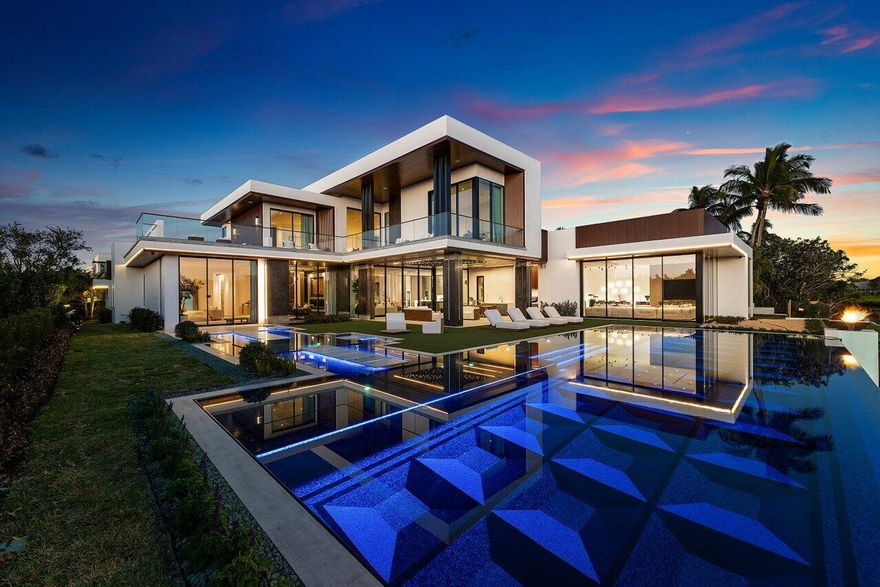 Step into unparalleled luxury in this brand-new custom estate located in the prestigious guard-gated community of Admirals Cove. Perfectly positioned on a quiet cul-de-sac just steps from the main clubhouse. This residence offers effortless access to world-class amenities, dining, spa, golf, and marina. A dramatic travertine and silver-leaf feature wall welcomes you, while the floating Cristallo staircase serves as a striking architectural centerpiece. Offering approximately 9,971 SF under air and 12,600 SF total. The home features 5 bedrooms including a first-floor primary suite, 6.1 baths, MAFI Austrian wood floors, and exceptional craftsmanship throughout. Two designer kitchens include a chef's kitchen and a stunning show kitchen with illuminated Cristallo quartzite countertops Ultra-high-end Eggersmann cabinetry, professional-grade appliances, and a custom coffee center define the designer kitchen. The primary bedroom is a serene retreat with La Finestra glass walls opening to the spa and pool, plus a spa-inspired bath with backlit agate countertops, integral stone sinks, dual water closets, freestanding soaking tub, titanium-tiled shower, and two custom walk-in closets.

First-floor features include a VIP guest suite, two powder rooms, elevator, striking office, clubroom, hair salon, butler's pantry, formal dining room, wine room, laundry and dog wash station. 
The private wellness suite offers a state-of-the-art gym, white aspen finishes, infrared sauna, red-light and salt therapy. 
The office showcases custom Brazilian teak blocks with brass inlays and a stone biofuel fireplace. 
A tranquil family lounge overlooks the pool, gardens, and golf course.
Upstairs offers a loft and three VIP suites with balconies capturing water, mangroves, and fairway views.
 
The resort-style outdoor living features a Euro-edge heated and chilled saltwater pool with lap lanes, fire bowls, spa, sun shelf, summer kitchen with pizza oven, cabana bath, retractable screens, premium sound, and lush privacy landscaping.

Additional highlights include 11'9" ceilings, Cristallo underlit countertops, La Finestra windows and doors, two exotic stone fireplaces, Crestron smart home technology, full-house generator, VRF climate system and high-tech security. The air-conditioned five-car garage offers 13' ceilings, EV charging, and lift capability. 

Front Entry: Elegant stainless steel sculpture by renowned artist, Alexander Krivosheiw featured in Architectural Digest. 

Required Admirals Cove golf membership includes two clubhouses, 45 holes of championship golf, marina, yacht club, five restaurants, tennis, pickleball, spa, salon, fitness, and kids club. Close to PBI.
 A rare and irreplaceable offering.

BUILDER: Boca Raton Custom Homes 
ARCHITECT: Randall Stofft