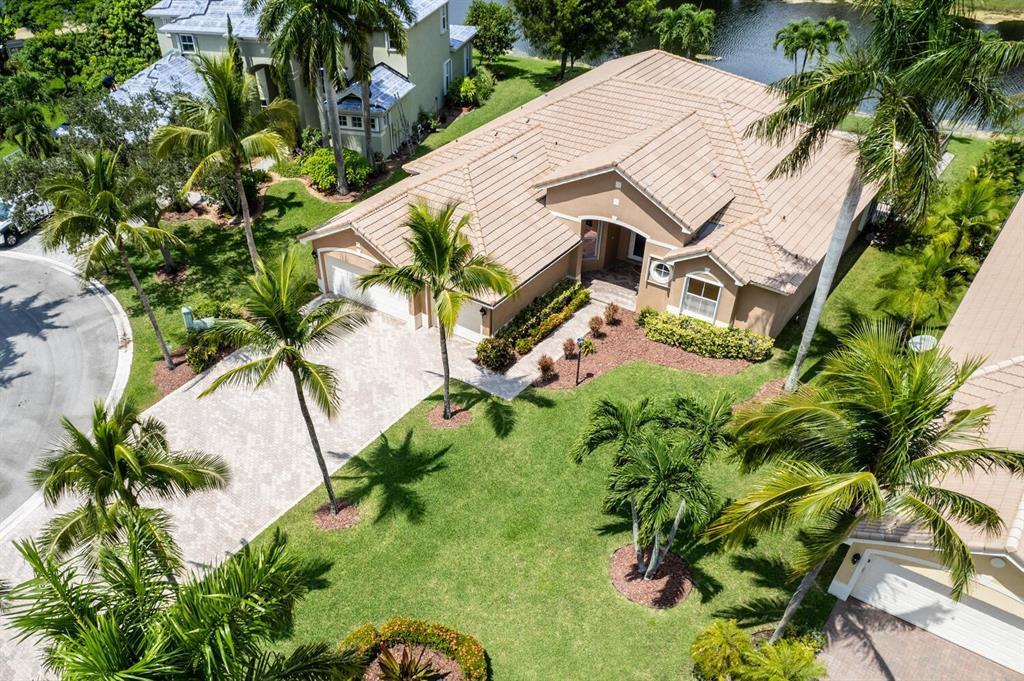 Set in the prestigious estate section of Parkland Isles, this stunning home offers impressive curb appeal and magnificent water views. Inside, you'll find tray and volume ceilings, crown molding, and recessed lighting throughout. Light, neutral tile extends across the foyer, living room, dining room, kitchen, family room, utility room, and fourth bedroom. The gourmet kitchen features elegant cabinetry, granite counters, a breakfast bar, and a walk-in pantry. The 3-way split bedroom layout ensures privacy, with the master suite boasting custom closets, a sitting area, and water views. The master bath includes a double vanity, whirlpool tub, and separate shower. Accordion shutters, impact doors, and a large paver driveway and patio complement the fenced pool area.