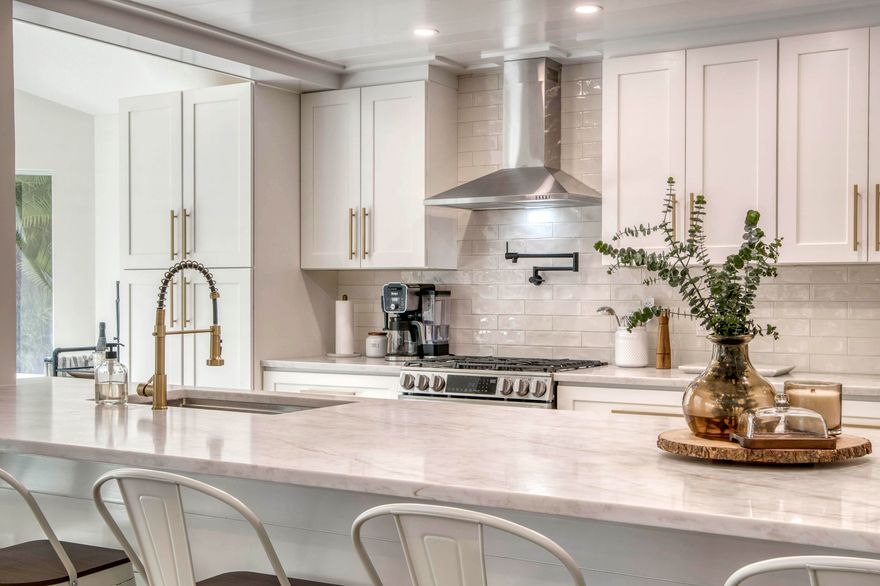 Welcome to 18867 Big Cypress Drive in Jupiter, a beautifully remodeled home showcasing high-end finishes and a relaxed coastal design. This light-filled residence features a 2019 metal roof, impact windows and doors, an impact garage door, aluminum hurricane panels, and large 59'' Italian wood-look porcelain tile flooring throughout. The open floor plan centers around a stunning chef's kitchen with custom wood cabinetry, Taj quartz countertops, ceramic tile backsplash, stainless range hood, pot filler, and an LG 6-burner gas range with oversized island seating for six--perfect for entertaining. Shiplap coastal design details add warmth and character throughout the home. The dining area offers high ceilings, impact windows, and French doors leading to a screened lanai and pool area designed for seamless indoor-outdoor living. The spacious primary suite includes plantation shutters and direct access to the lanai, while the updated bathrooms feature custom vanities and designer finishes. Outside, enjoy a private backyard retreat with new landscaping, fencing, stepping stones, upgraded pool equipment, French drain and irrigation improvements, and a screened patio with lighting and fans. Additional highlights include recessed lighting throughout, epoxy garage floors, a Carrier A/C (2019), ADT security system, and an owned in-ground propane tank.