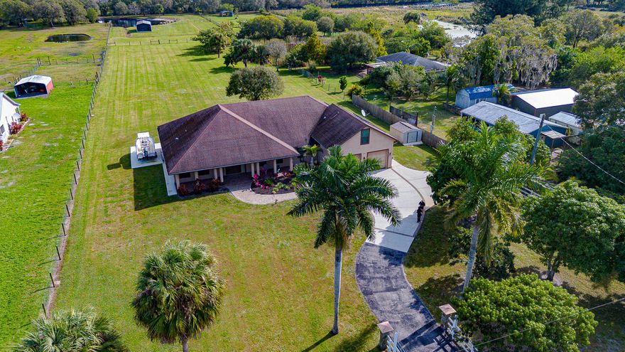 Welcome Home! This beautifully maintained, custom ranch home on 2.99 fenced acres at the end of private paved road features 4 beds + game room/office/ possible 5th bedroom, 3.5 baths, & 2.5-car garage. Master features HIS/HERS baths & HIS/HERS Walk In Closets! Enjoy stunning views of lakes, wildlife, & mature landscaping. Boasting cathedral ceilings, a chef's kitchen w/ Cherrywood cabinets, quartz counters, & top-tier gas stove. Entertain with ease in the 880 sq ft screened lanai w/ full outdoor kitchen & fireplace or relax in the saltwater pool w/ solar heat. Includes a 2-stall barn, RV/boat pad with 220V, whole-house reverse osmosis, HUGE walk in insulated attic, central vac, & more just 10 mins to beaches & 2 miles from I-95 & Turnpike! Seller offering low % financing Surrounded by manicured grounds, mature oaks, tropical palms, fruit trees (including three varieties of mangoes), and scenic views of two shared lakes populated with swans, ducks, and native birds. Across from private land filled with deer and antelope this property is truly a peaceful rural retreat.

Step onto a paver walkway leading to a charming covered porch with custom wood ceilings and lighting. Enter through double fiberglass doors with side panels and built-in blinds into a cathedral-ceiling living space with elegant trim, custom fan, chandelier, and spacious layout. The semi-open concept kitchen is a chef's dream featuring Cherrywood cabinetry with soft-close doors/drawers, pull-out trays, a lazy Susan, under-cabinet lighting, quartz countertops, and top-tier stainless steel appliances including a double oven and six-burner gas cooktop.

Enjoy meals in the coffered-ceiling dining room or the octagon-shaped breakfast nook with Tiffany lighting and serene views. Step out onto the impressive 880 sq ft screened lanai with custom wood ceilings, four ceiling fans, recessed lighting, and a full outdoor kitchen with gas grill, sink, fridge, granite counters and fireplace all connected to a 120-gallon propane tank. The adjacent cabana bath offers a heated shower and storage.

Cool off in the 36'x15' saltwater pool with sun deck, upgraded tile border, stamped concrete deck, and solar heat system all fenced for privacy and safety. The master suite occupies the entire southern wing with a private rec room, dual walk-in closets, and dual full baths. Zoned A/C with a 5-ton Arcoaire 2-stage system, air scrubber, and dehumidifier keep the home comfortable year-round.

Additional features:

2.5-car garage with workshop and remote doors

Above-garage guest suite with bedroom, half bath, and closets

Whole-house reverse osmosis water system and solar hot water

Central vacuum, hurricane-impact windows, wood blinds, shutters

Concrete pad with 220V for boat/RV parking

Aluminum barn with 2 stalls, tack room, water, and electric

Landscaped back acre with firepit and mature trees

Lighted 10x12 aluminum shed on slab

Just 10 minutes to the beach, marinas, dining, and shopping. Only 2 miles to I-95 and Turnpike. Enjoy peace, privacy, and practicality all in one extraordinary estate! RECENTLY REDUCED BY $151,000! SELLER IS MOTIVATED!