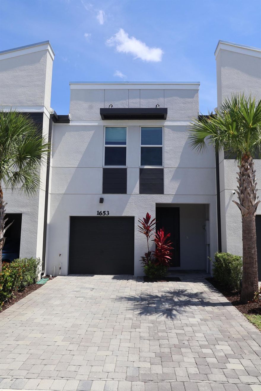 Must-see modern townhome in the heart of West Palm Beach! This beautifully maintained 2022-built Nickel model offers 1,485 sq ft of open living space with 3 spacious bedrooms, 2.5 bathrooms, and a 1-car garage. Built with energy-efficient block construction, impact windows, spray foam insulation, and stylish upgrades throughout. Enjoy a bright, open floorplan with a large kitchen island, flexible upstairs loft, and walk-in laundry room. Features include modern pebble shaker cabinets, granite countertops, wood-look tile flooring downstairs, and wood flooring upstairs--no carpet! Located in the gated community of Enclave at Mangonia, offering a pool, cabana, and tot-lot. Just 3 minutes from I-95 and close to everything!