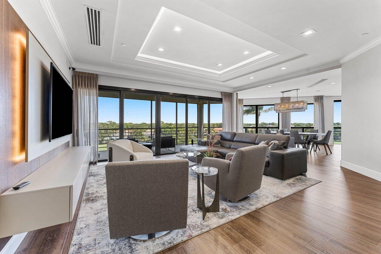 The Chateau at Boca Grove blends the sophistication of country club living with the ease of luxury condominium life. This meticulously renovated and elegantly appointed home in the sky offers 3 bedrooms, 3.5 bathrooms, and a den, spanning nearly 3,900 square feet. Panoramic lake and golf course views frame the open floor plan, designed for seamless entertaining. The chef's kitchen features Jenn-Air appliances, designer cabinetry, and a custom backlit bar. A semi-private elevator opens directly into the residence, enhancing both privacy and convenience. Additional highlights include a private full two-car garage located beneath the building. The luxurious primary suite boasts dual custom walk-in closets and a spa-inspired bathroom with separate water closets. Two spacious guest