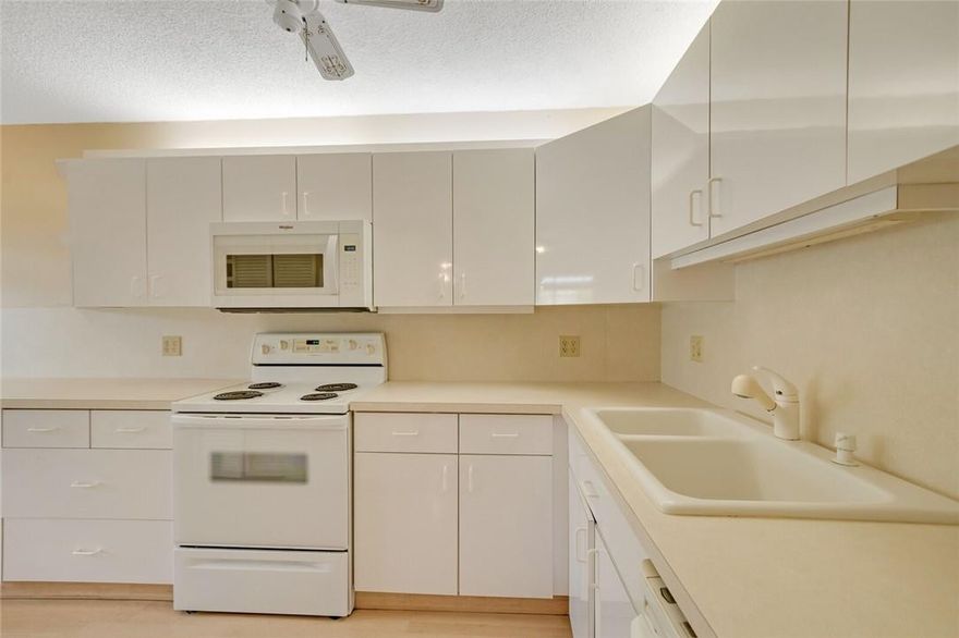 Rarely available 1st floor unit in the active 55+ gated community of Banyan Springs! This spacious floor plan features 2 large bedrooms, each with a walk-in closet and bathroom. The large living + dining room area features wood-look tile floors laid in a beautiful herringbone design. Brand new carpet & light fixtures installed in both bedrooms. Washer and dryer in the unit with a new water heater! Well protected from hurricanes with easy to operate accordion shutters throughout. While this unit is located in a very quiet area, you're just a short walk from all the wonderful amenities Banyan Springs has to offer, including: heated pool & spa, tennis courts, dining cafe, fitness center, pickleball, billiards, card room & more! Very social community with various events and clubs