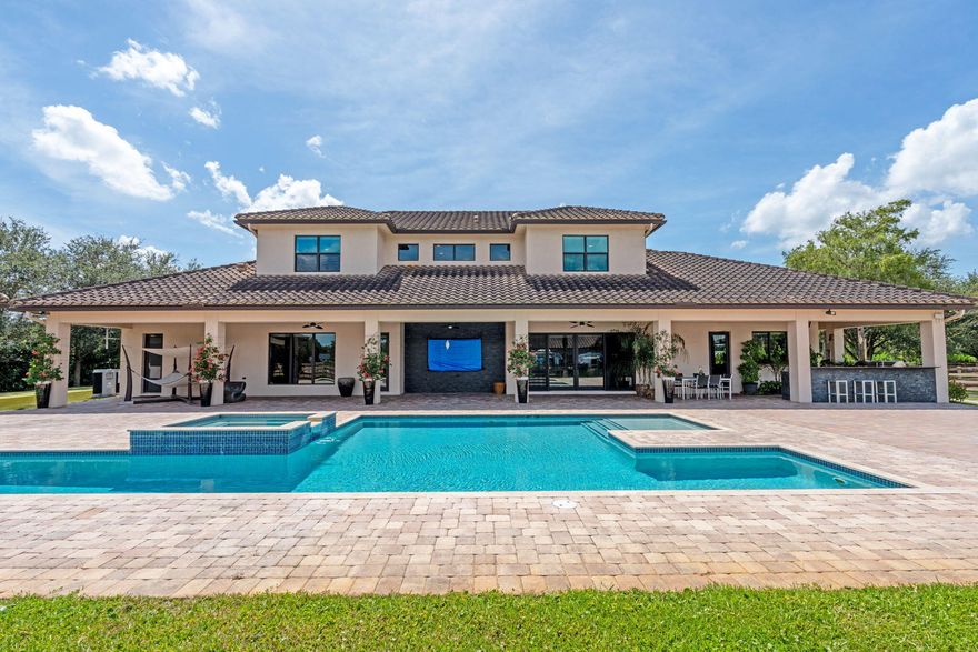 An equestrian dream opportunity: two adjoining properties totaling 3.75 acres with world-class equestrian facilities, including a fully equipped 7-stall barn with tack, feed, laundry, and full bath; a 5-stall barn with tack and feed rooms; multiple wash stalls; two all weather arenas; a hot walker; and five paddocks. Three gated driveways and mature landscaping provide privacy and ease of access, just minutes from the Wellington International, Global Dressage venues, and Wellington's dining and shopping—perfectly timed for show season. The main residence is a modern entertainer's dream with bright, wide-open spaces, soaring ceilings, and nearly floor-to-ceiling windows. The entry leads into a striking, one-of-a-kind wine room. Italian marble and wood flooring flow throughout, complemented by a custom office, formal dining, a gorgeous loft, and a spectacular kitchen with a huge center island, custom cabinetry, and a double pantry. An elegant indoor bar provides a separate space for entertaining.

The main-level primary suite is a luxurious retreat with dual spa-inspired bathrooms, a freestanding soaking tub, double vanities, a huge walk-in shower, a sitting area, an oversized closet, and a cabana-style bath. Living areas open to a resort-style pool with summer kitchen, putting green, and cabana bath. A 4-car garage, coffee bar, and state-of-the-art laundry with automated lighting complete the residence. A separate 1-bedroom apartment with a full kitchen and laundry provides private guest or staff accommodations.

The second residence offers 3 bedrooms, 2 baths, an office, formal dining, partial hurricane-impact windows, its own pool, a detached studio efficiency, and a 3-car garage.

This rare Wellington property blends luxury living with exceptional equestrian amenities, offering an unparalleled lifestyle for entertaining, leisure, and equestrian pursuits.