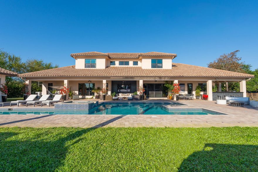 An equestrian dream opportunity: two adjoining properties totaling 3.75 acres with world-class equestrian facilities, including a fully equipped 7-stall barn with tack, feed, laundry, and full bath; a 5-stall barn with tack and feed rooms; multiple wash stalls; two all weather arenas; a hot walker; and five paddocks. Three gated driveways and mature landscaping provide privacy and ease of access, just minutes from the Wellington International, Global Dressage venues, and Wellington's dining and shopping—perfectly timed for show season. The main residence is a modern entertainer's dream with bright, wide-open spaces, soaring ceilings, and nearly floor-to-ceiling windows. The entry leads into a striking, one-of-a-kind wine room. Italian marble and wood flooring flow throughout, complemented by a custom office, formal dining, a gorgeous loft, and a spectacular kitchen with a huge center island, custom cabinetry, and a double pantry. An elegant indoor bar provides a separate space for entertaining.  The main-level primary suite is a luxurious retreat with dual spa-inspired bathrooms, a freestanding soaking tub, double vanities, a huge walk-in shower, a sitting area, an oversized closet, and a cabana-style bath. Living areas open to a resort-style pool with summer kitchen, putting green, and cabana bath. A 4-car garage, coffee bar, and state-of-the-art laundry with automated lighting complete the residence. A separate 1-bedroom apartment with a full kitchen and laundry provides private guest or staff accommodations.  The second residence offers 3 bedrooms, 2 baths, an office, formal dining, partial hurricane-impact windows, its own pool, a detached studio efficiency, and a 3-car garage.  This rare Wellington property blends luxury living with exceptional equestrian amenities, offering an unparalleled lifestyle for entertaining, leisure, and equestrian pursuits.