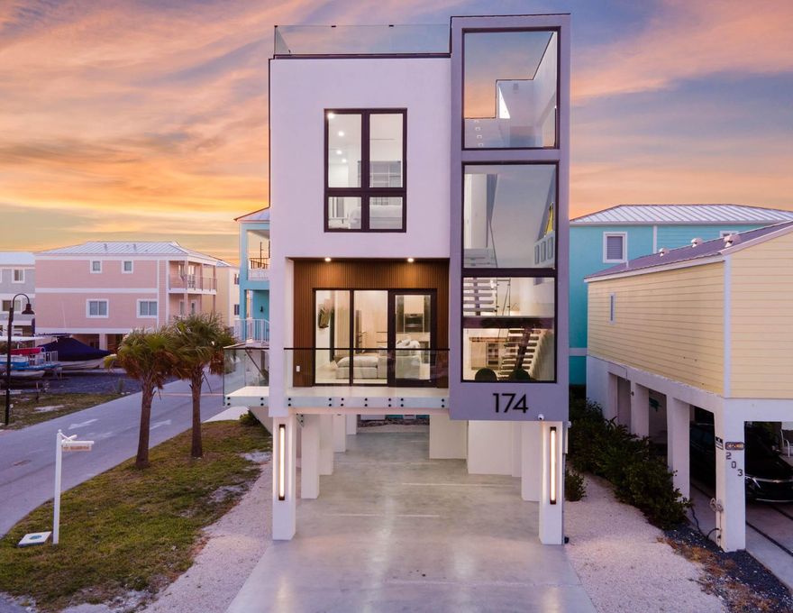 This brand-new, turnkey, Hamptons-inspired, architectural stunner offers the finest in modern coastal living. Thoughtfully constructed by Dennis Construction and designed by CSpace Architecture, this concrete block, full impact glass home is built with elegance and function at the forefront.Step into nearly 2,160 square feet of open-concept living space where 24x36 oversized ceramic tile floors, recessed LED + cove lighting, and a curated Restoration Hardware furniture package set the tone for upscale comfort. The kitchen is a showstopper with an ultra-luxe Samsung appliance suite, sleek finishes, and custom cabinetry.  Enjoy a private elevator, two-zone A/C + dehumidifier, and unwind on your fully finished rooftop - complete with a built-in grill and sweeping ocean views.