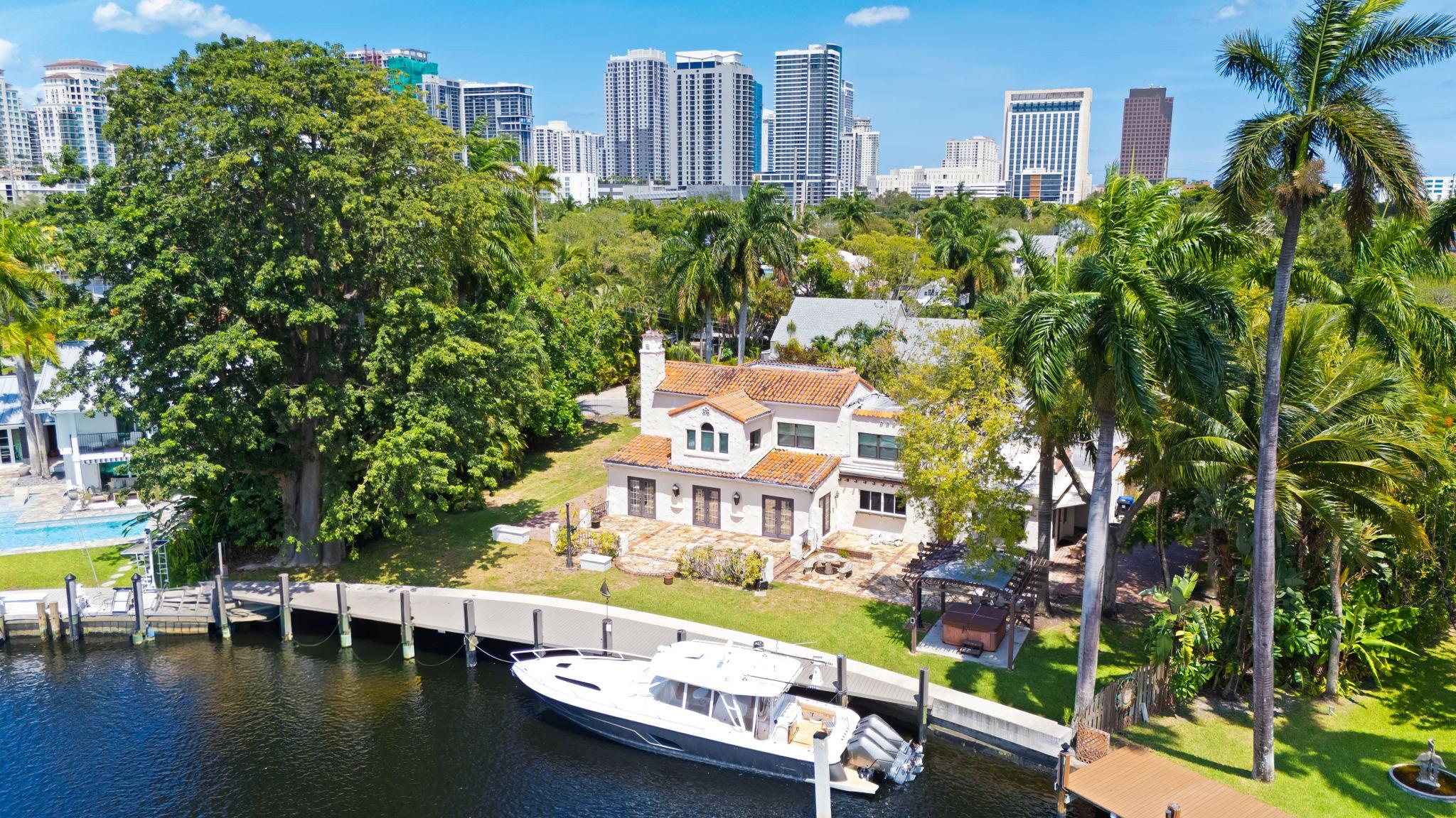 Fort Lauderdale’s most exceptional waterfront estates. Nestled within the gated enclave of Tropical Point, the 3,420 sq. ft. home sits on over half an acre with 118 feet along the South Fork of the New River, balances historic charm with water views of “Little Florida.”. Original details—arched French doors, fireplaces, hardwood floors, and curved entryways—blend seamlessly with modern enhancements including a rebuilt staircase, brand-new tankless W/H, updated roof work, additional A/C, and a new 118-foot seawall & dock. A 3-car garage, one bay fully air-conditioned. The primary suite upstairs enjoys a private balcony with breathtaking views, while the main level offers formal and casual living spaces, dining, kitchen with butler’s pantry, 2 laundry rooms, and an exterior powder bath.