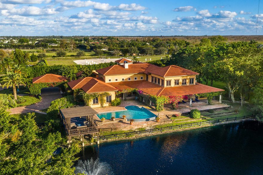 Nestled in a delightful peaceful area in Wellington, this Spanish style house brings you everything you need for a great investment in a 10 acres property. This two-story home includes a ground-floor master suite and five additional bedrooms; three of which are located on the second floor . Enjoy the view of your horses from the second floor 600 sqft studio. Unique designs in the living and dining areas both overlooking the oversize infinity pool. Impressive custom made wine room. Good size exercise room with sauna and steam room. This property features a 12,000 sqft barn with 24 stalls, 2 apartments, grooms quarters, jumping arena, dressage arena and plenty of paddocks. It also features a fly spray system, wash stalls and a security system. Freshly painted. Amazing property!