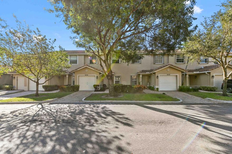 Prepare to be mesmerized by this one-of-a-kind townhome, where vibrant artistic design meets an ideal functional layout. The exterior features attractive Mediterranean architecture with a tile roof and a brick-paver walkway leading to the covered entry and attached garage. The living room boasts soaring vaulted ceilings and is bathed in light, flowing seamlessly through sliding glass doors to the screened patio. The dining area is highlighted by a glamorous, oversized gold-framed mirror and a classic chandelier. The kitchen is efficiently laid out with warm wood cabinetry, granite counters, and stainless steel appliances.
