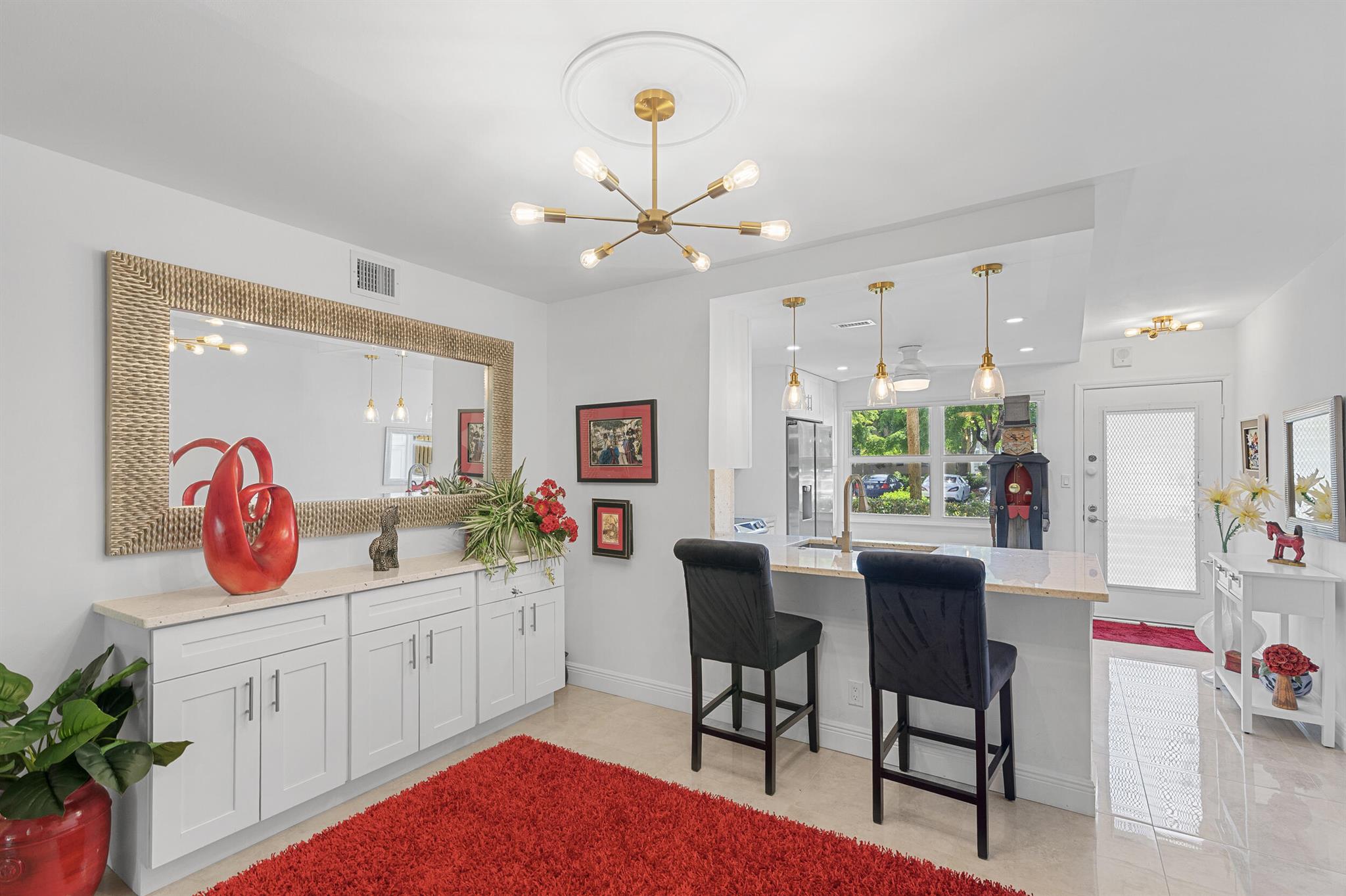 This exquisite 2BD/2BA 1st floor condo has been meticulously renovated with high-end finishes. Porcelain tile flooring and high-impact hurricane windows ensure elegance and safety. The open-concept kitchen boasts thick quartz countertops, shaker-style cabinets, stainless steel appliances, and full-height backsplash. A built-in quartz buffet enhances the dining area, perfect for entertaining. Luxurious bathrooms feature premium vanities, showers, and fixtures. Enjoy custom closets, designer lighting, barn doors, a new AC handler, and panoramic sliding glass doors with motorized window treatments, overlooking lush gardens. Assigned parking and storage with unit. All designer furniture and accessories are negotiable. Wynmoor offers pickle ball, golf, theatre, cafe on the green and MUCH MORE!