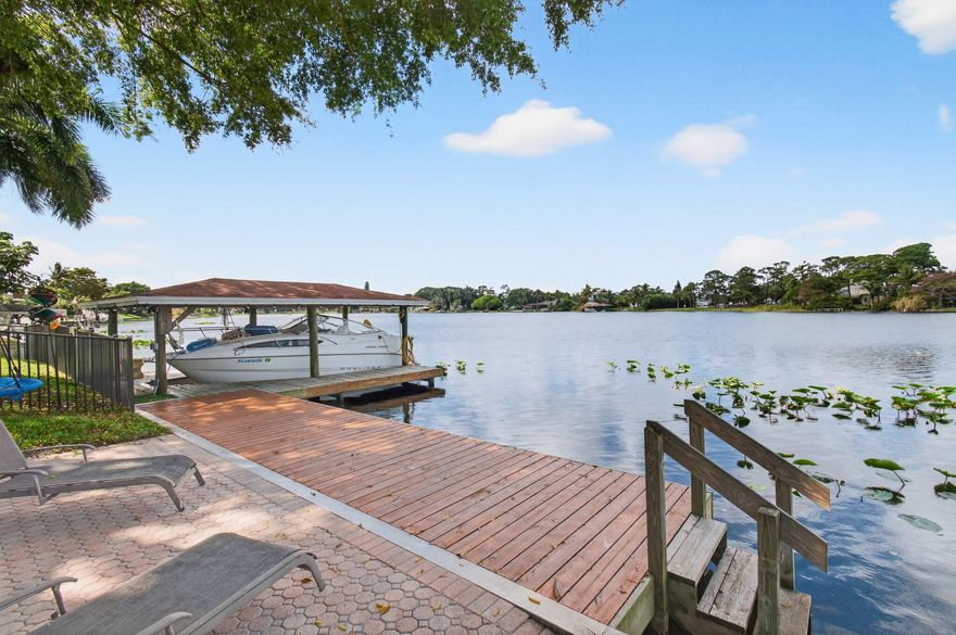 WELCOME TO PARADISE! Renovated waterfront home on Lake Osborne with stunning views and a majestic banyan tree. Updated kitchen with quartz countertops and black stainless appliances (2020). New roof (2025), hot water heater, and washer/dryer (2022). Enjoy a covered dock  access to 5 lakes and 80 miles of waterways, plus a brand new $21K hot tub and upgraded landscaping. Walk or boat to Hive Waterfront Restaurant & Tiki Bar. Detached 360 sq ft A/C space—perfect office, gym, guest suite, or income opportunity.
