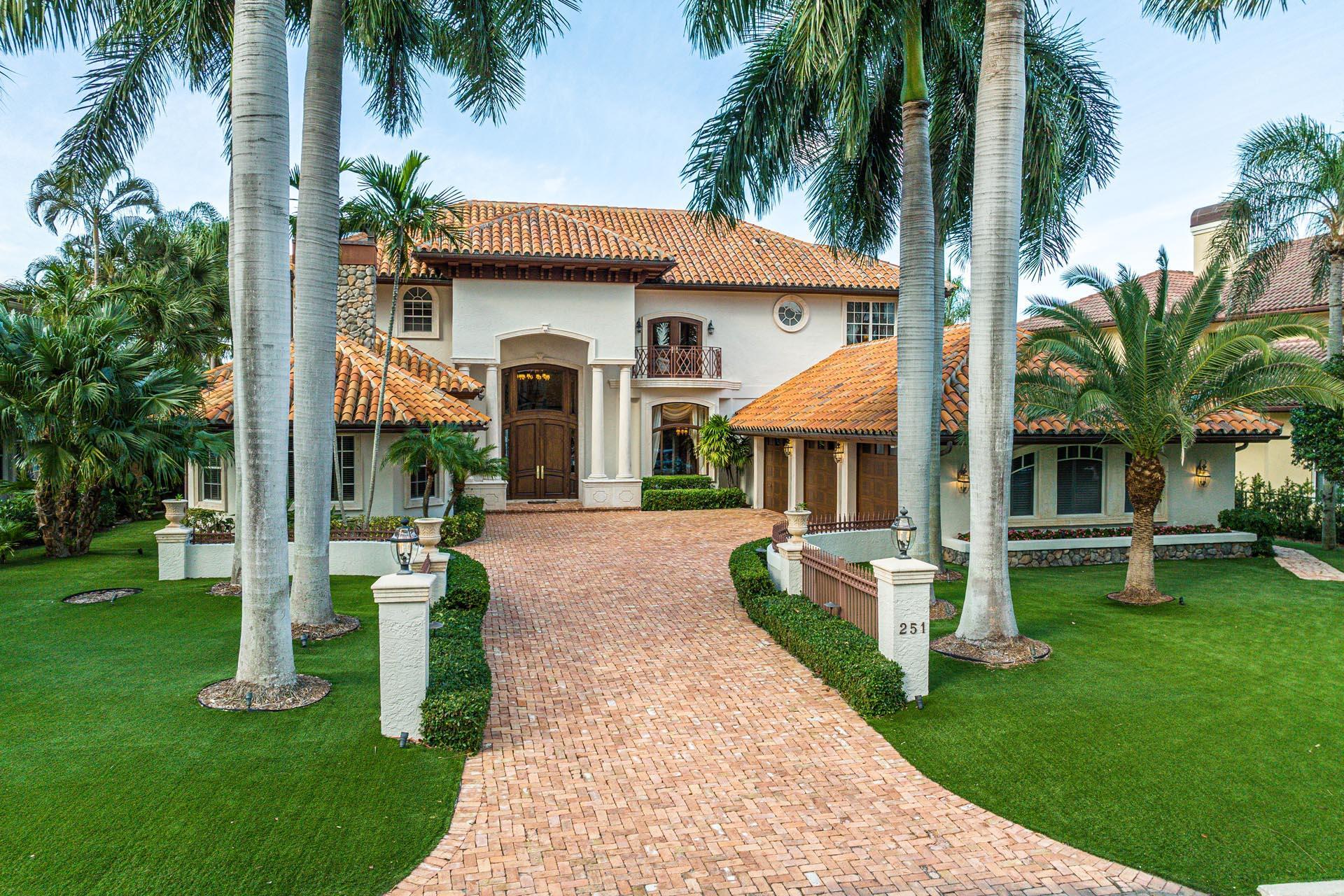 Introducing a waterfront masterpiece designed for those who value privacy and luxury living. This exceptional estate offers 89 feet on the widest canal in Royal Palm Yacht & Country Club and features a private dock with a boat lift, providing direct access to the Intracoastal. With sunny north exposure, the expansive outdoor living area boasts a heated free-form pool and spa surrounded by an elegant paver deck, creating an ideal space for relaxation or entertaining.The large covered patio is perfect for al fresco dining and features a striking spiral staircase leading to the VIP suites and balcony, offering serene water views. Inside, the gourmet eat-in kitchen with a spacious island and walk-in pantry meets the culinary needs of any chef, while the formal dining room, highlighted