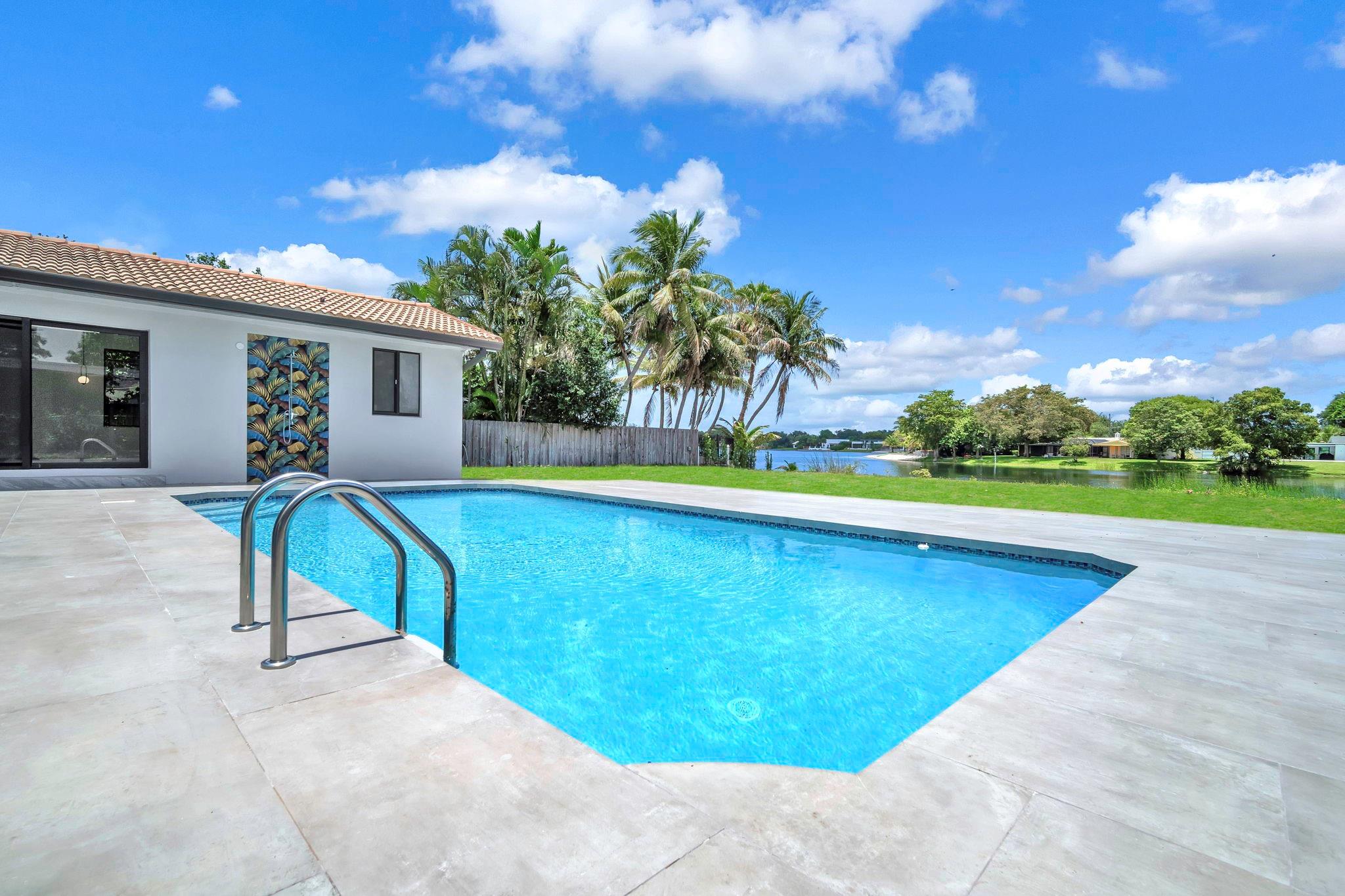 This stunning lakefront home blends luxury, efficiency, and smart tech with direct frontage on tranquil Greyknoll Lake—no HOA! Features include brand-new insulation, impact windows/doors, dual ACs, smart controls, and two water heaters. The chef’s kitchen boasts two 100” islands, double sinks, double Bosch dishwashers, and a 72” Monogram fridge/freezer with deluxe Shabbos mode. Includes dual ovens and an induction cooktop. Spa-like primary suite offers a soaking tub, 7’ rainfall shower, and smart commode. Gorgeous 40”x40” Italian porcelain tile throughout, oversized pool, tropical outdoor shower, EV charger, reverse osmosis system, and lake-fed irrigation.