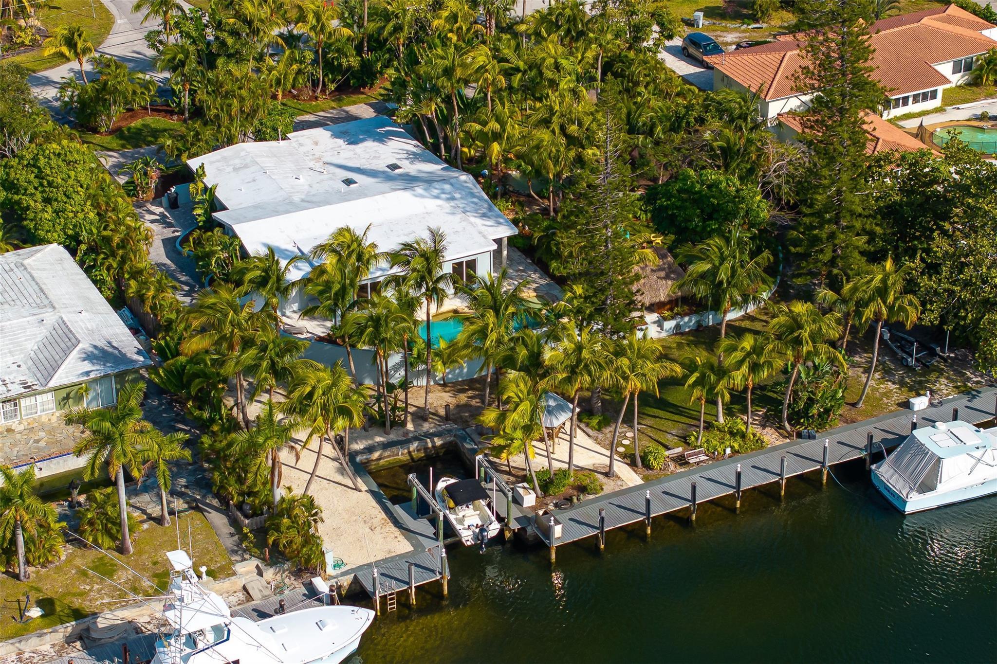 Welcome to The Hibiscus House! This one-of-a-kind Pompano retreat sits on a rare 30,000 sq ft lot surrounded by lush, tropical landscaping reminiscent of Costa Rica. This 4-bed, 4-bath oasis features 3 tiki huts, a pond with waterfall, pool, jacuzzi, and mature trees creating a private paradise. Boaters will love the 150-ft dock with boat lift on a deep canal--just 8 minutes to the ocean. Elevated property with impact windows, travertine floors, and a renovated kitchen overlooking the exotic grounds. A true South Florida gem!