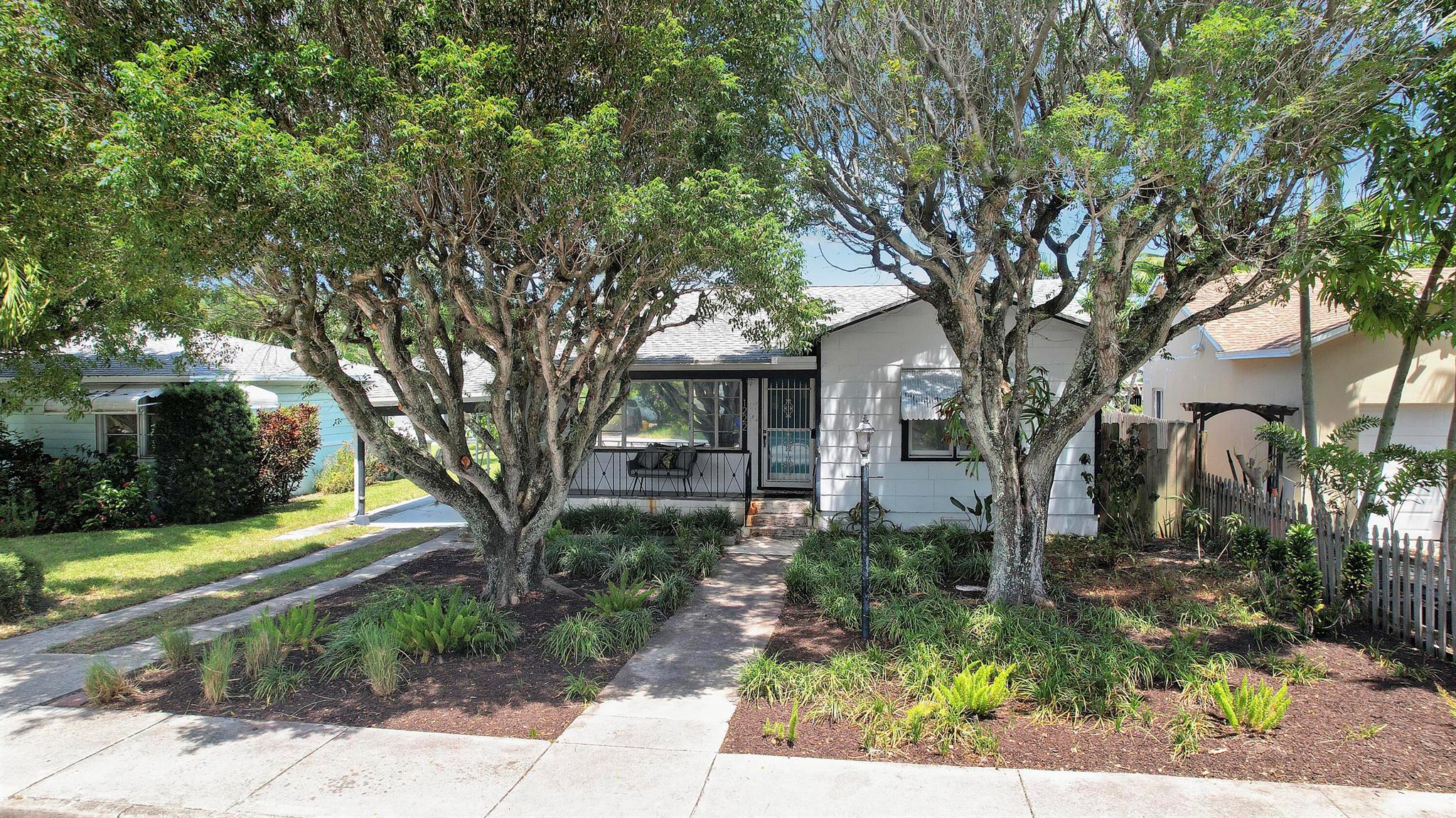 Welcome to this charming 2-bedroom, 1.5-bathroom home in Lake Worth Beach, priced to sell! Located just minutes from the beach and trendy downtown Lake Worth Beach, this home sits on an oversized, fully fenced lot with mature mahogany trees in the front yard and an adorable front porch. Recent extensive foundation work includes a 25-year warranty. The open kitchen boasts white shaker cabinets and stainless appliances. Original Dade County pine floors add warmth, and the spacious bedrooms offer rare closet space for a home of this era. A 1500 AMP generator provides peace of mind during storm season. Plenty of room for a pool or addition--perfect as a first home or investment!