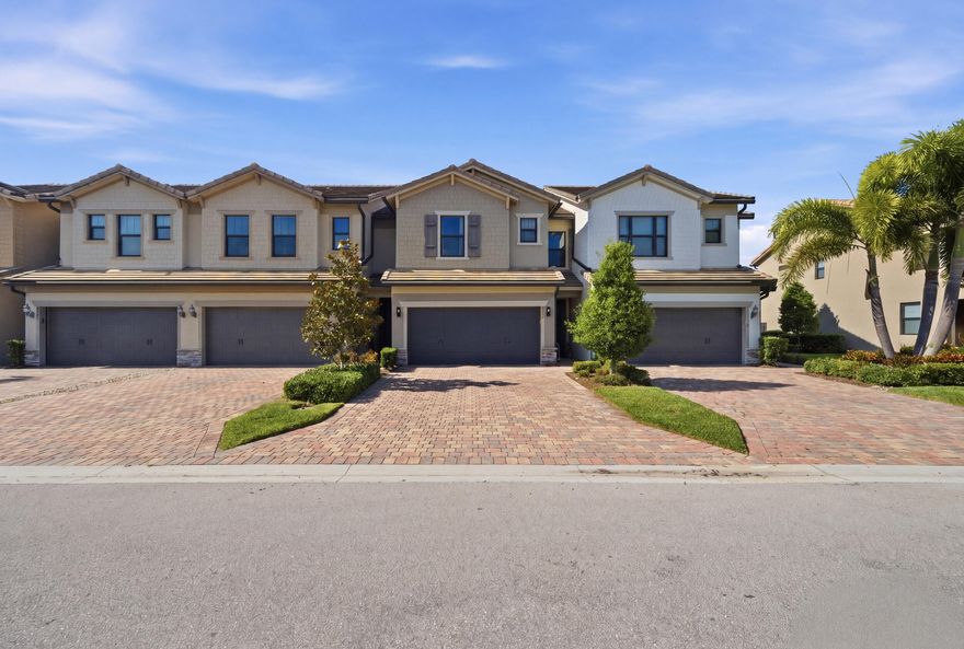 Welcome home to this stunning 3-bedroom, 2.5-bathroom townhome featuring a 2-car garage in the highly desirable gated community of The Fields. Built in 2020 by DiVosta and situated within an A-rated school district, this property impresses from the moment you arrive with its lush landscaping and elegant brick paver driveway. The interior continues to showcase premium attention to detail, boasting full impact glass for peace of mind and beautiful, vertically laid wood-look tile flooring throughout the main living areas. The space is illuminated by recessed lighting and updated fixtures, creating a bright and modern atmosphere.  The heart of the home is the fully open-concept kitchen, which seamlessly integrates with the living and dining rooms. It is equipped with a massive island featuring a unique half-moon cutout for bar-top seating, adorned with stylish pendant lighting. The chef-inspired space offers 42-inch solid wood shaker cabinetry, pristine white quartz countertops, a designer backsplash, and stainless steel appliances. Functional additions like a dedicated coffee bar, snack bar area, dual sink with disposal, and a pantry make this kitchen as practical as it is beautiful, further complemented by extra storage tucked under the stairs. Large sliding impact doors lead from the living area to your private screened-in patio, perfect for indoor-outdoor entertaining, while a conveniently located half-bath serves the main floor.  Retreat to the generous primary suite, where large windows invite an abundance of natural light to highlight the elegant tray ceiling. This sanctuary includes his-and-hers walk-in closets and a luxurious ensuite bathroom featuring an oversized solid wood vanity with granite countertops, dual sinks, and updated hardware. The spa-like experience is completed by a floor-to-ceiling tiled walk-in shower with a framed glass enclosure and integrated niche shelving. The two additional bedrooms are equally spacious, featuring ample natural light, updated fixtures, and a walk-in closet in one. They share a well-appointed secondary bathroom with solid wood cabinetry, quartz countertops, and a fully tiled shower-tub combo. For ultimate convenience, the dedicated laundry room is located upstairs, offering plenty of space and functional wire rack shelving for organization.  Living in The Fields offers a low-maintenance lifestyle, as the HOA fee covers irrigation, landscaping, common area maintenance, and security. Residents enjoy world-class amenities, including two community pools, tennis courts, and a full fitness center, all within a secure gated entry. This home perfectly blends modern luxury with community comfort in one of the area's most sought-after neighborhoods.