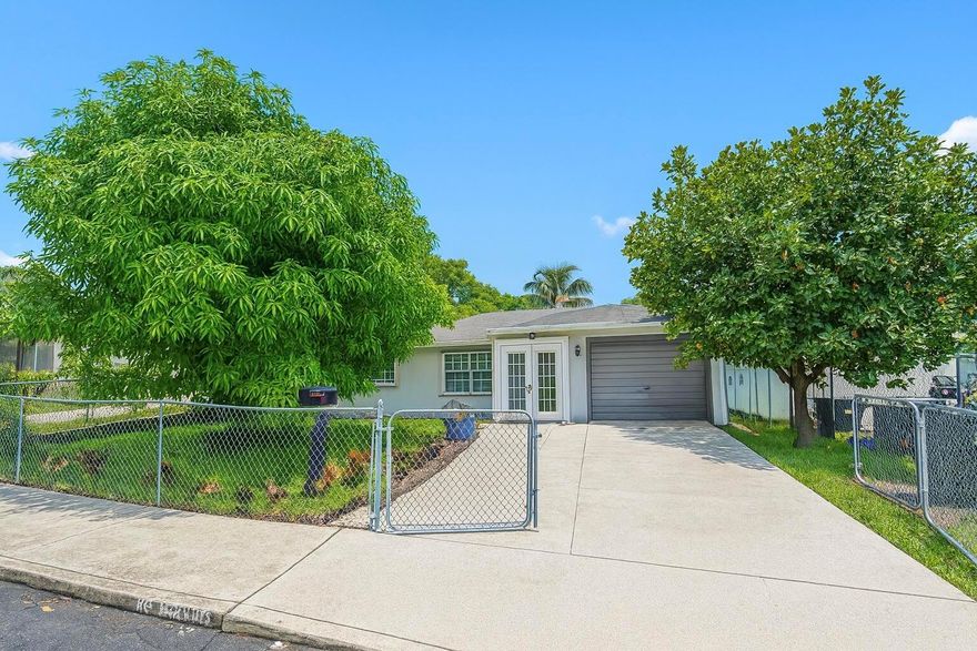 Step into this beautifully updated South Florida home with brand-new, modern renovations throughout. The chef-style kitchen features quartz waterfall counters, bold veining, soft-close shaker cabinets, matte-black hardware, stainless appliances, and a designer backsplash. The open layout includes recessed lighting and contemporary fixtures. Both bathrooms are fully updated with frameless glass showers, rainfall heads, marble-look tile, and modern vanities. Bedrooms offer fresh paint, large-format porcelain tile, and ample closets. Outside features a fenced yard, mature fruit trees, gated entry, and a large driveway. Move-in ready and close to everything.